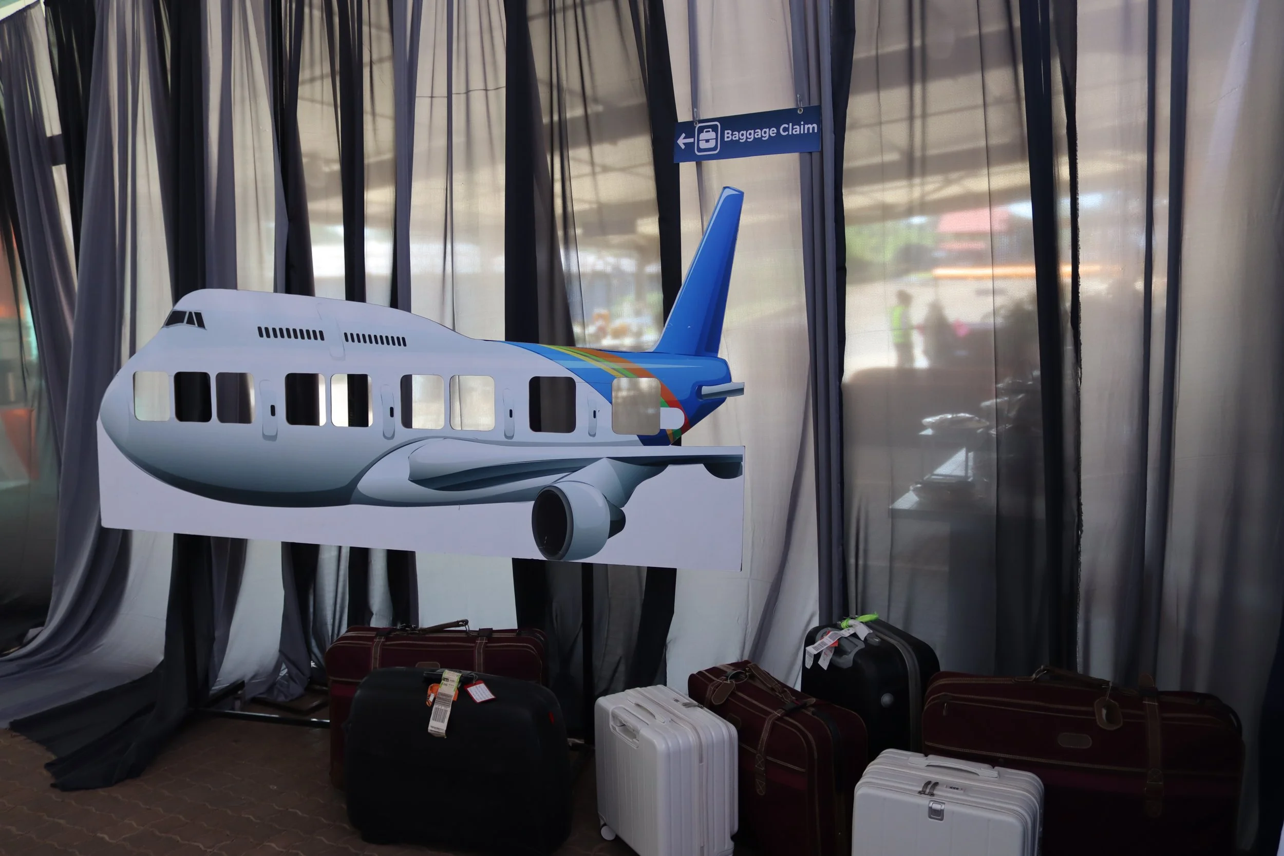 Sign indicating baggage claim area in an airport, with luggage and model airplane.