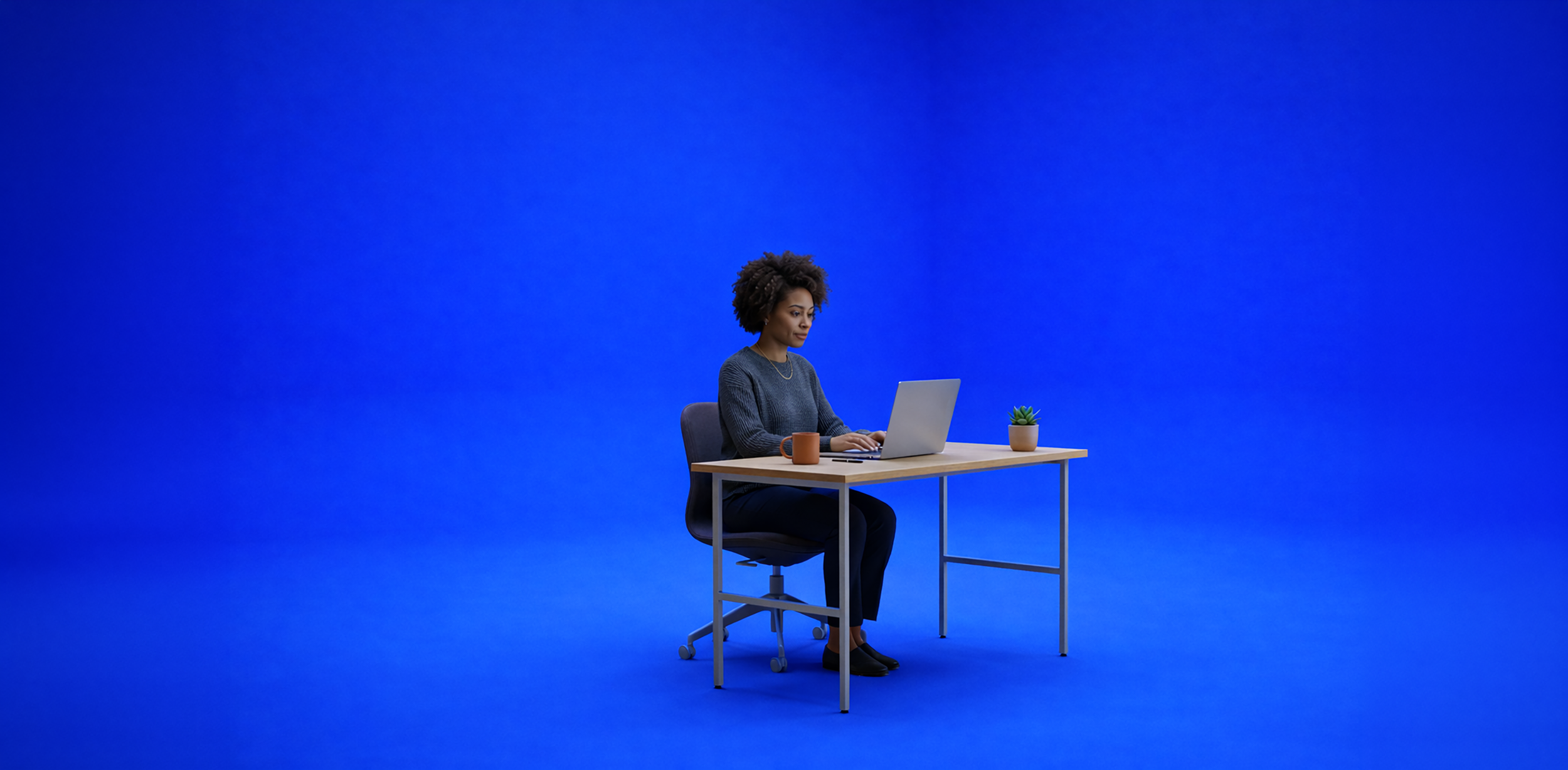 A woman sitting at a desk working on a laptop, with a coffee mug and a small potted plant on the desk, against a solid blue background.