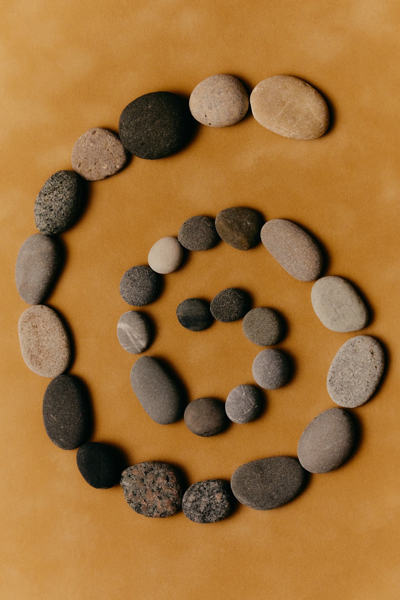 Arrangement of various smooth stones on a brown surface.