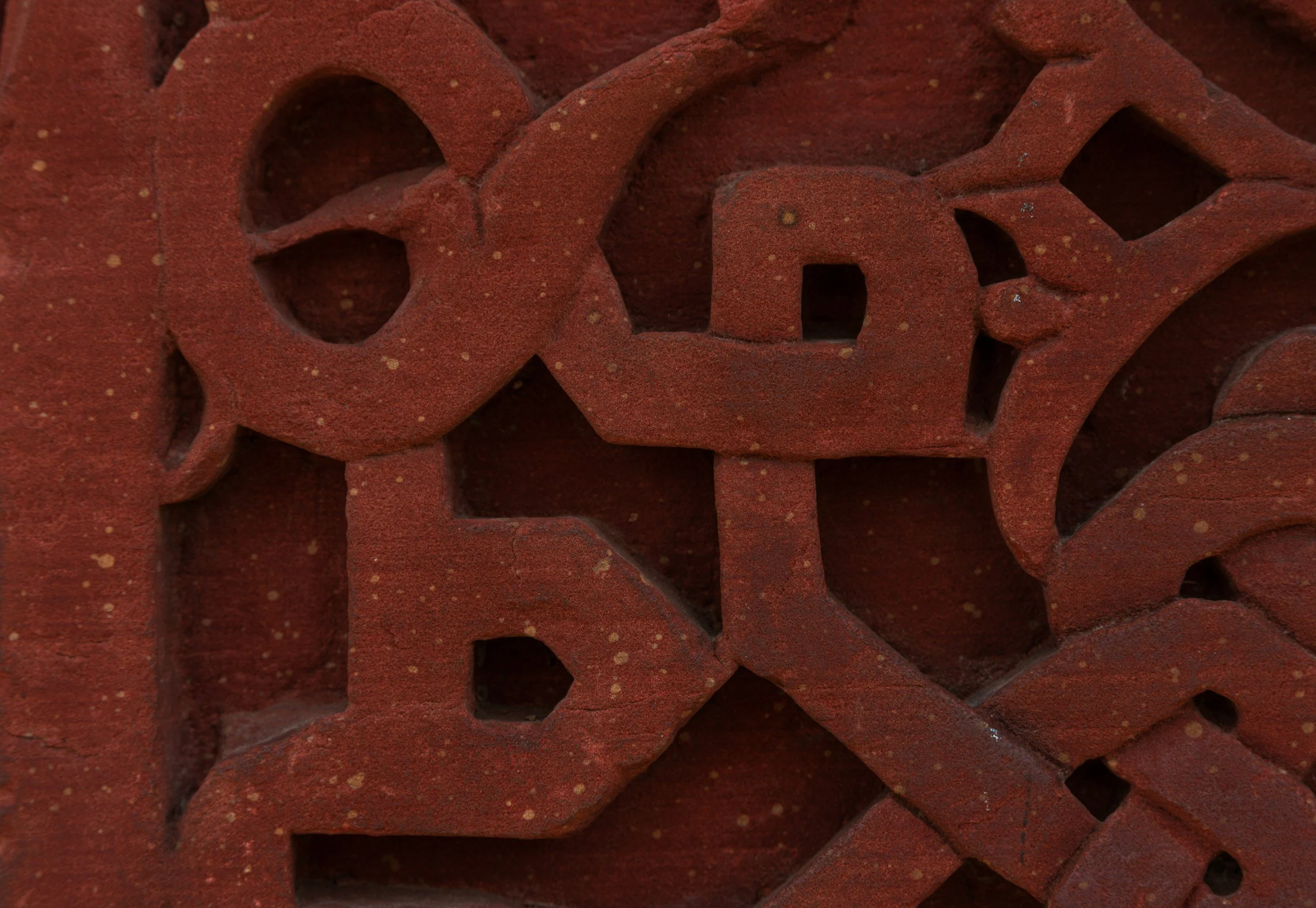 Close-up of red decorative bricks with cut-out patterns, some with small yellow speckles.