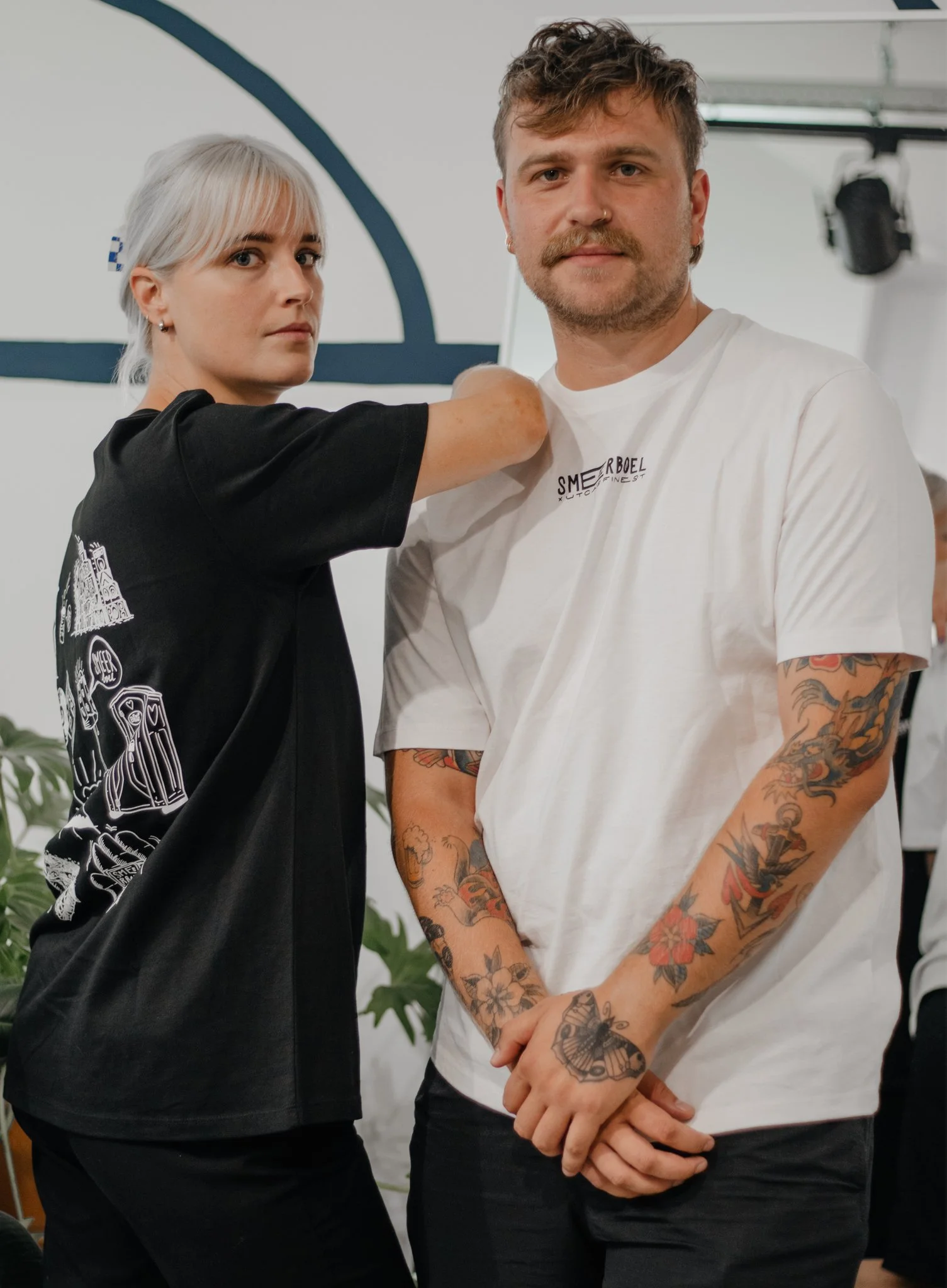 Een man met getatoeëerde armen en een vrouw met een blond kapsel die een vaccin inspuiten.