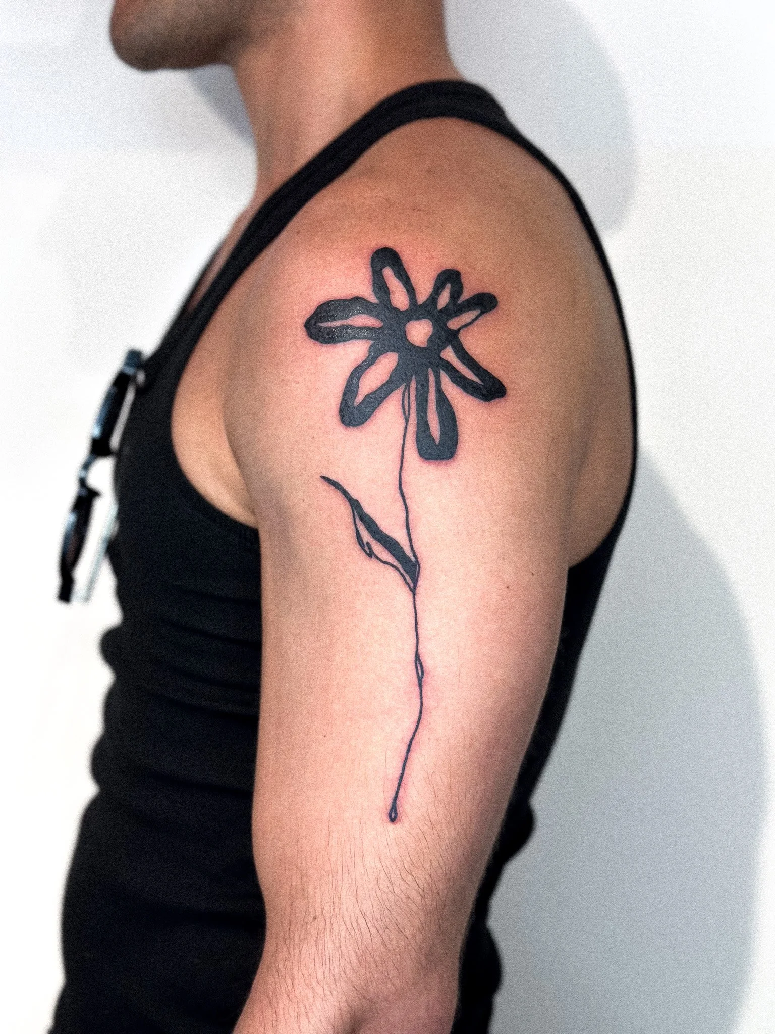 Close-up van een persoon met een bloemen-tatoeage op de schouder en bovenarm.