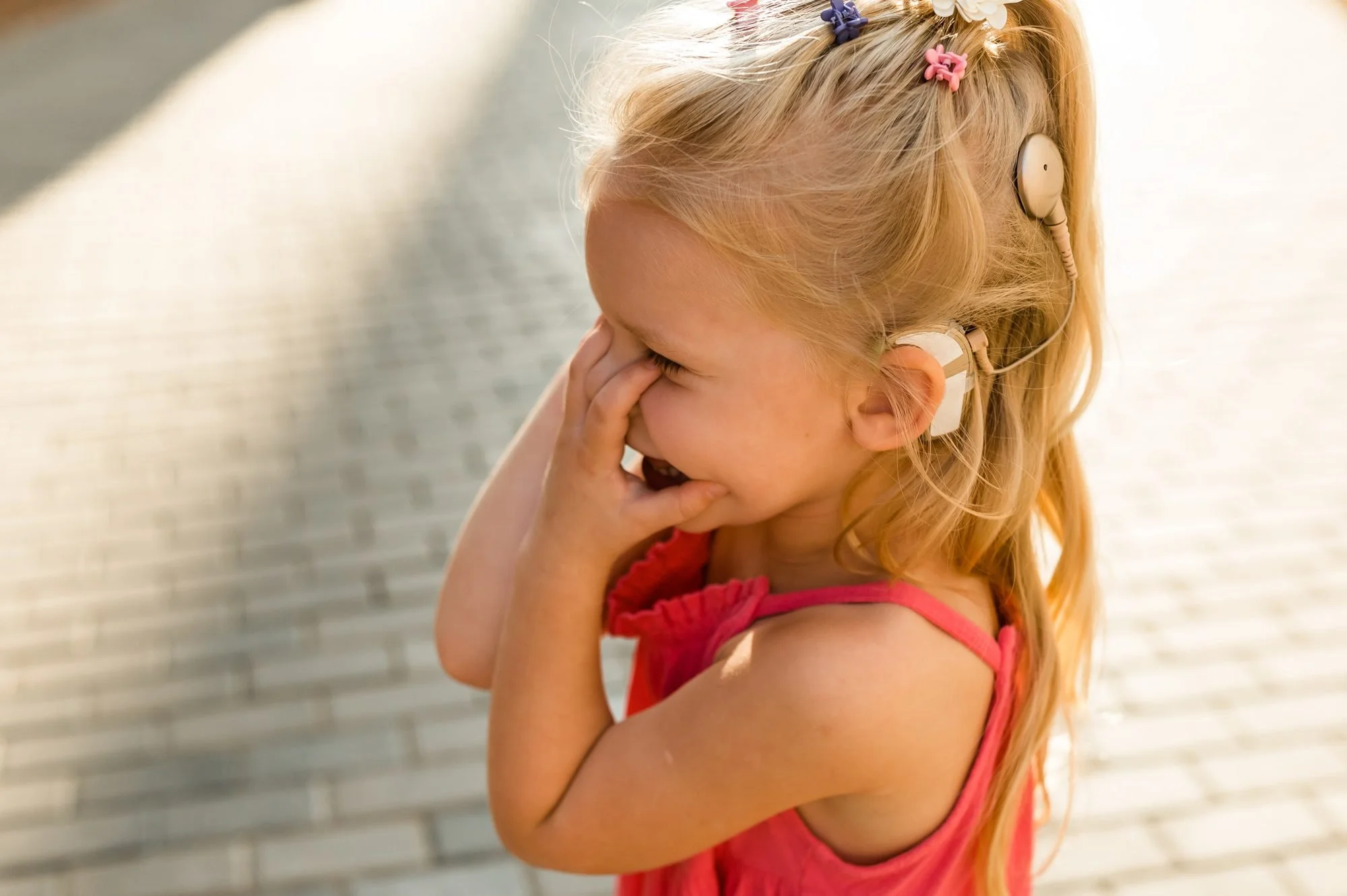 Fillette appareillée qui rit, la main devant la bouche