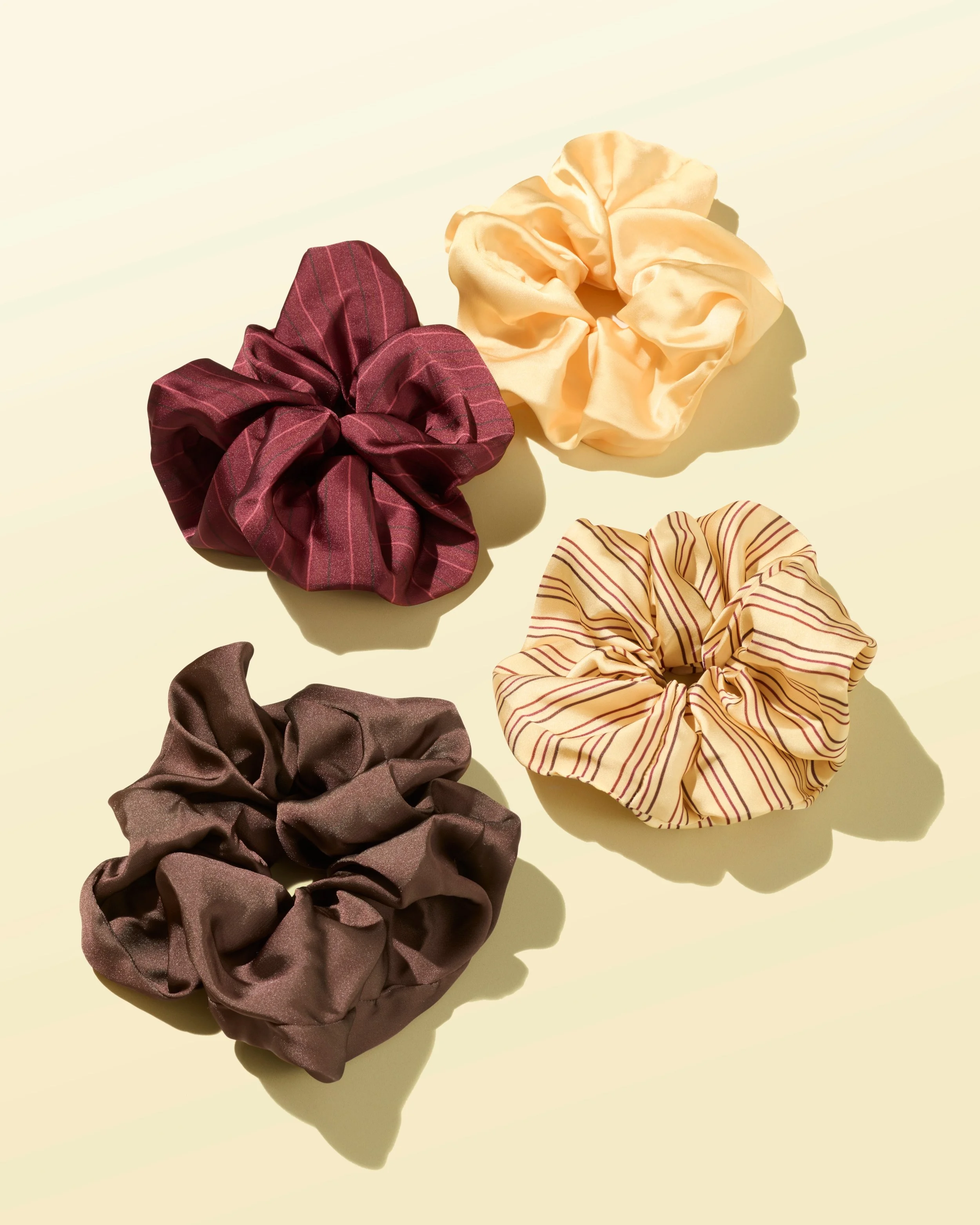 Scrunchies in yellow, red, cream and brown against a yellow background