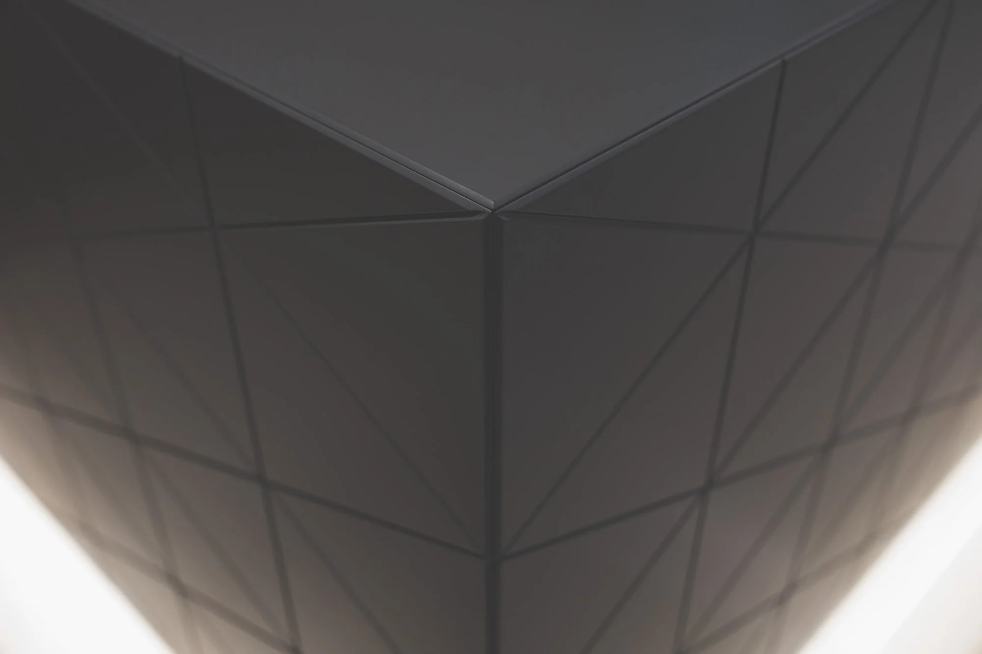 Close-up of a black geometric object with intersecting lines, creating a pattern of triangles.