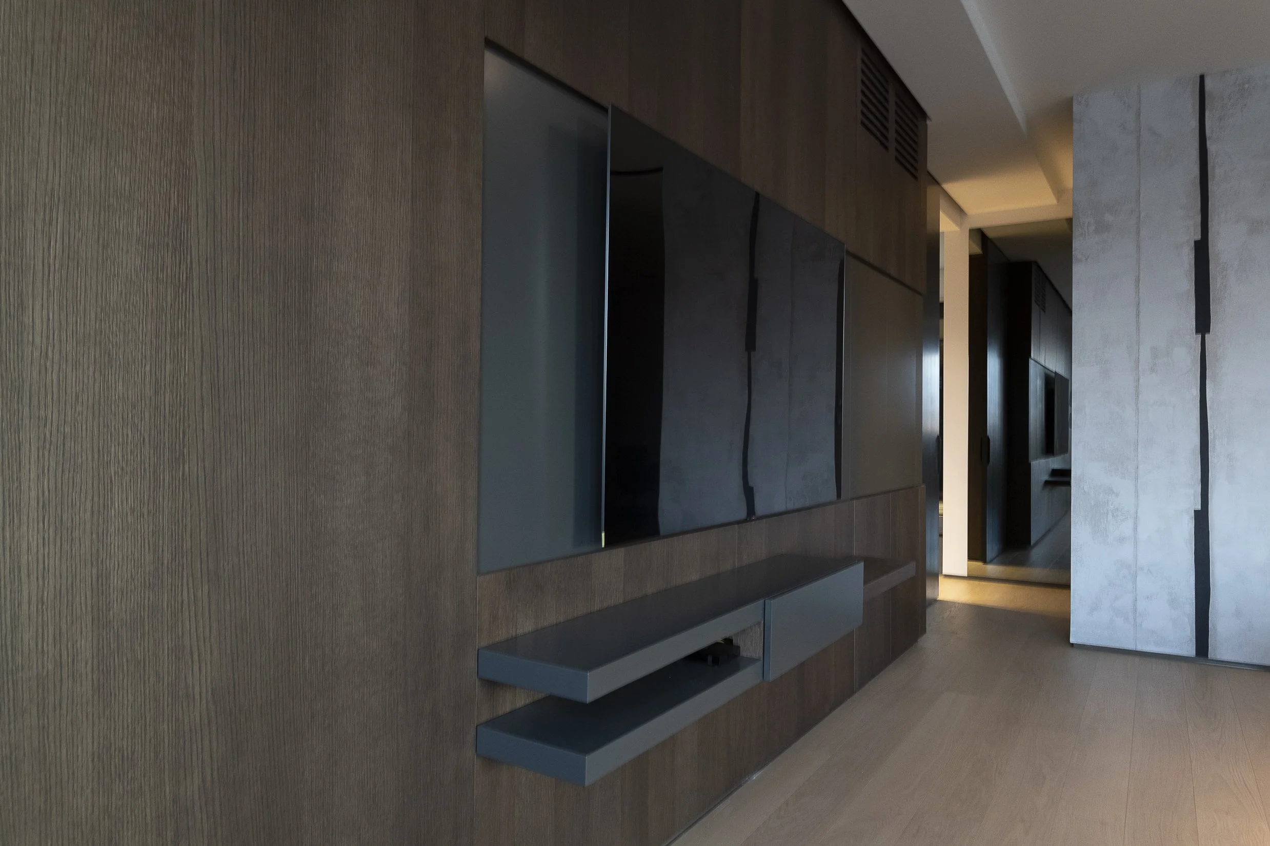 Modern interior with wooden paneled walls, flat screen TV, and a light gray stone partition in a sleek living room.