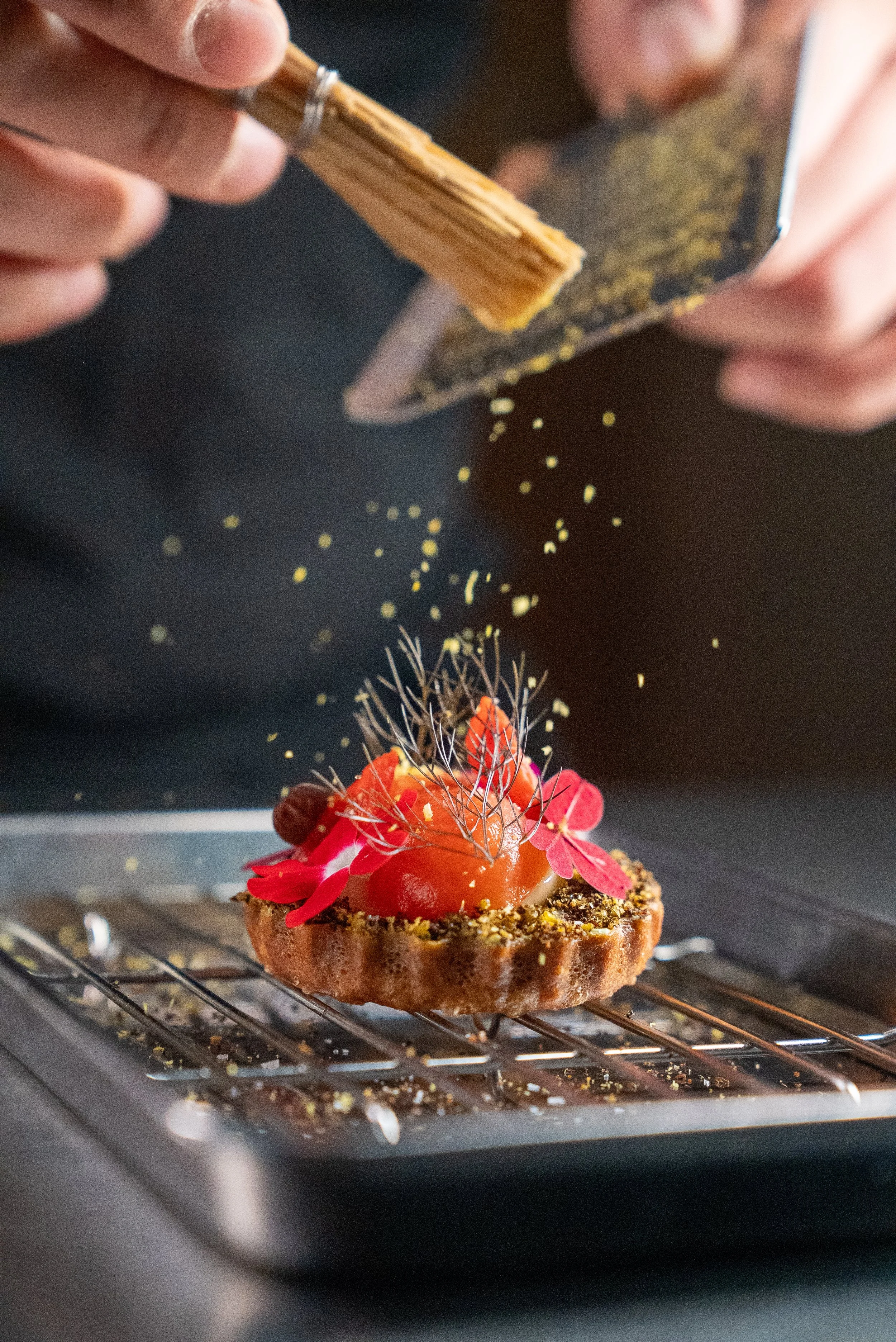 small tomato tartlet being zested with yuzu and lemon