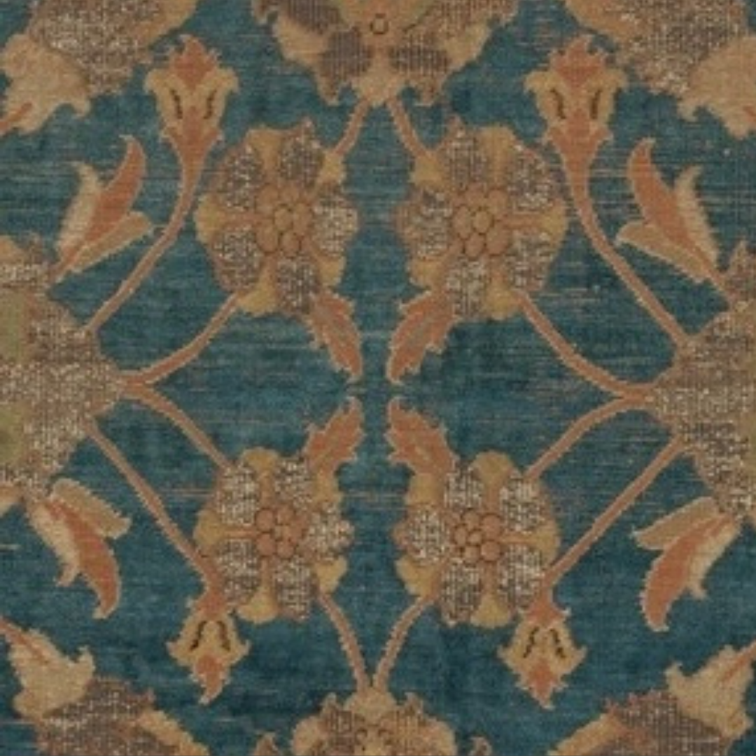 A colorful, patterned rug with floral and leaf motifs in shades of blue, beige, orange, and cream.