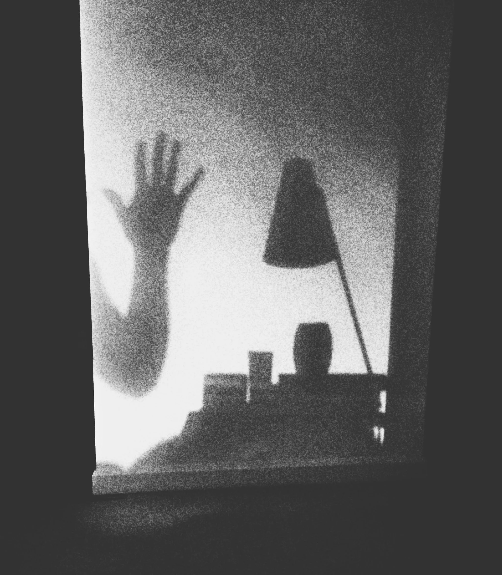 Dark black-and-white photograph of a silhouetted hand and abstract shapes against a window.