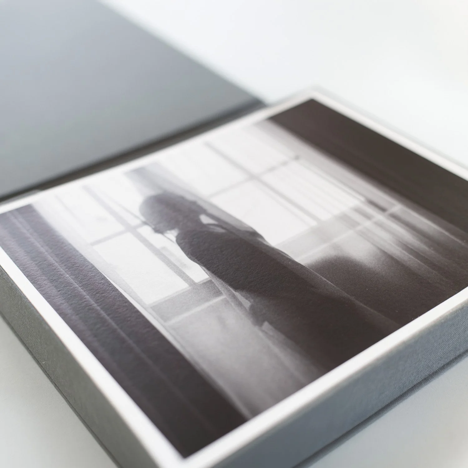 Detail of a black-and-white fine art print of a silhouetted woman standing beside a window.