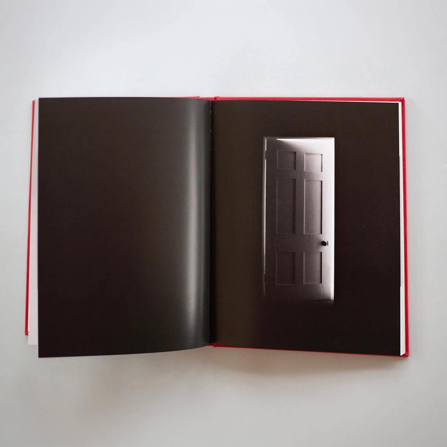 Open I Also Fight Windmills photobook showing a black-and-white photograph of an illuminated doorway.