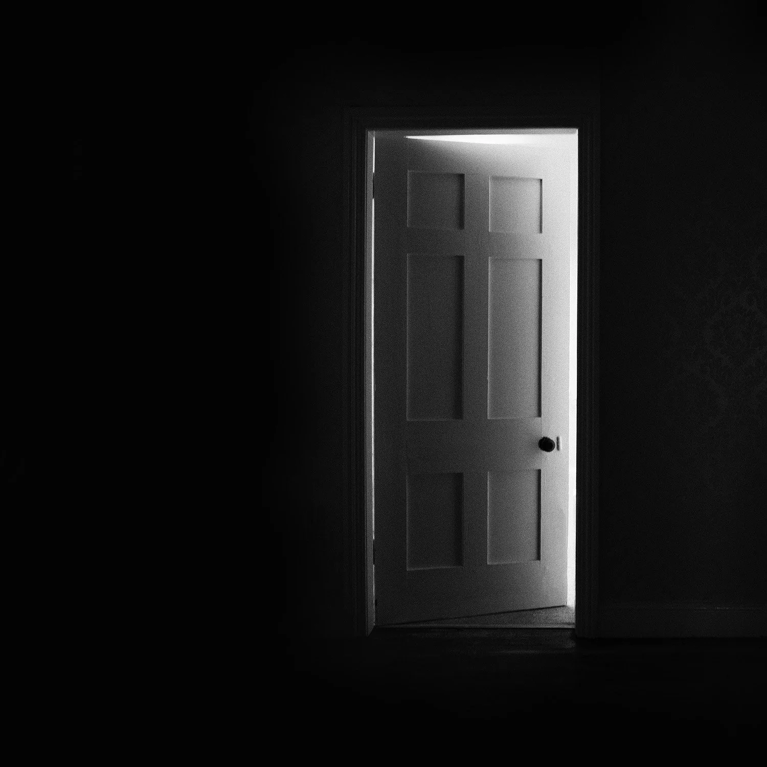 Detail of The Door by Ania Ready, showing light entering a dark room through a partially open door.