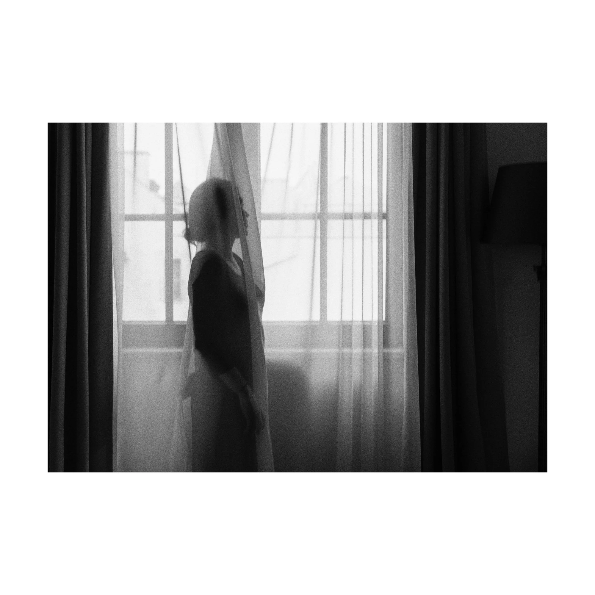 Veiled, black-and-white photograph by Ania Ready showing a silhouetted woman behind a translucent curtain.