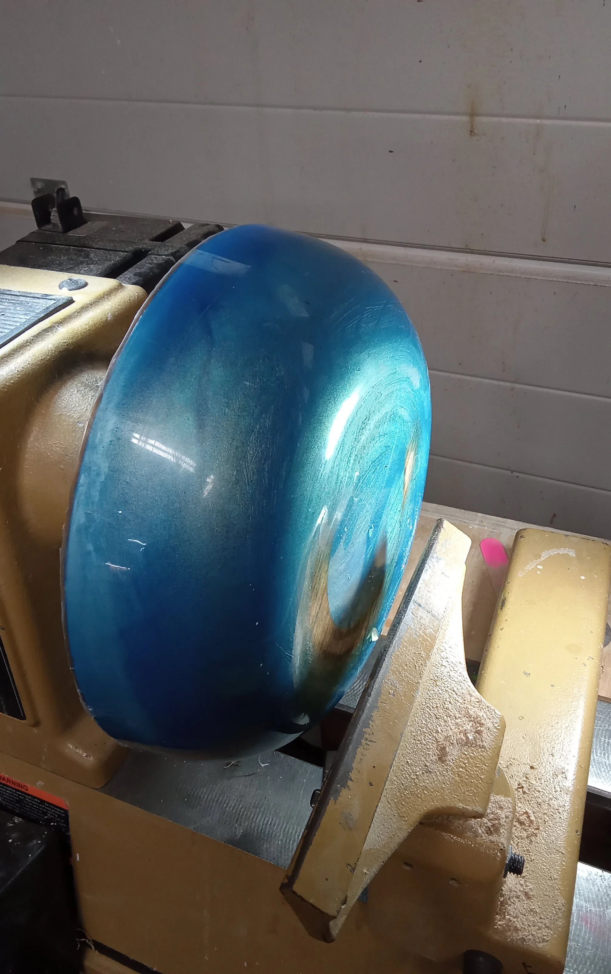 Blue resin art piece being shaped and finished in the Art by Herb workshop.