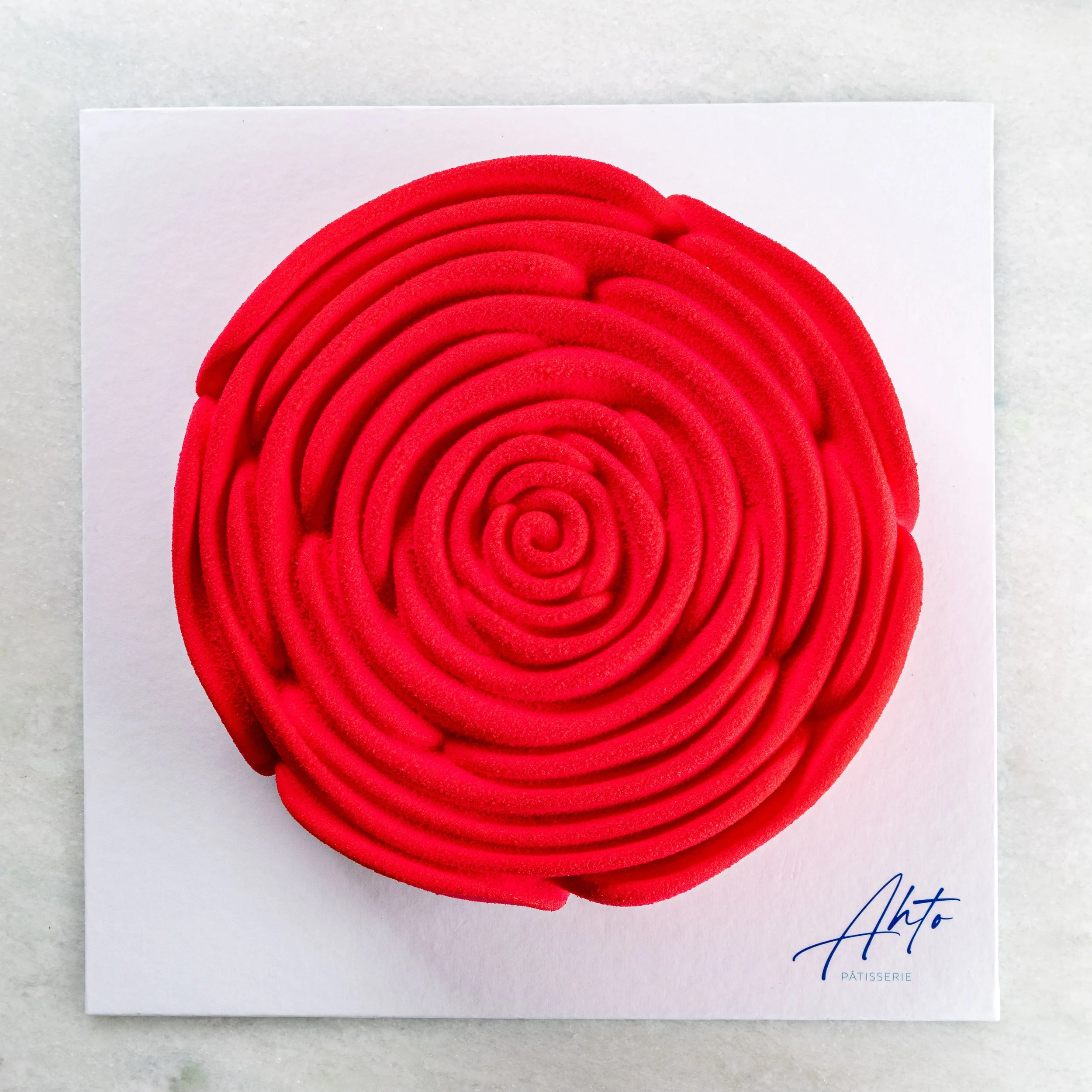 Entremet Fleur da Ahto Pâtisserie, com acabamento vermelho em formato floral e apresentação minimalista.