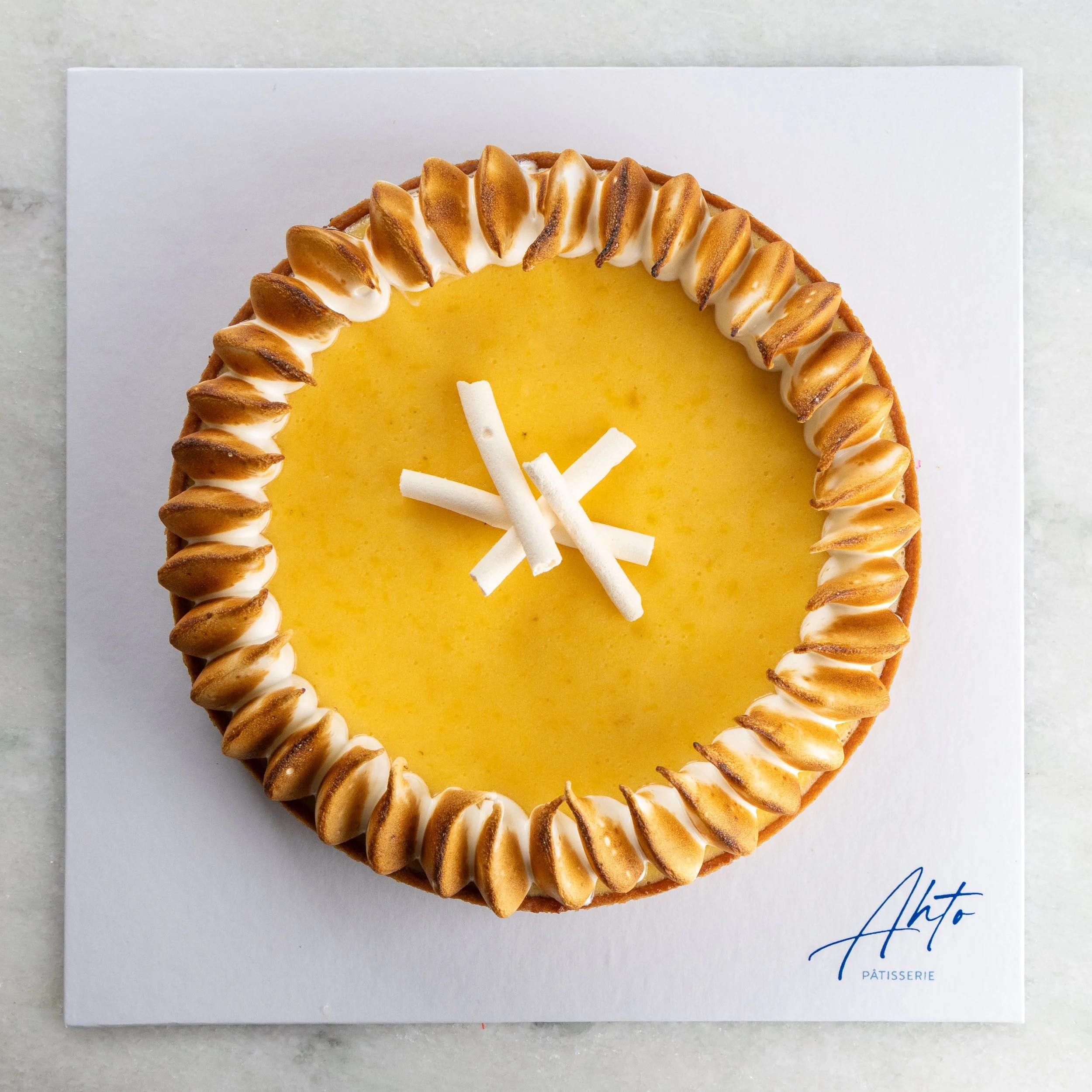 Torta de yuzu da Ahto Pâtisserie, com creme de yuzu, acabamento maçaricado e decoração central de chocolate branco.