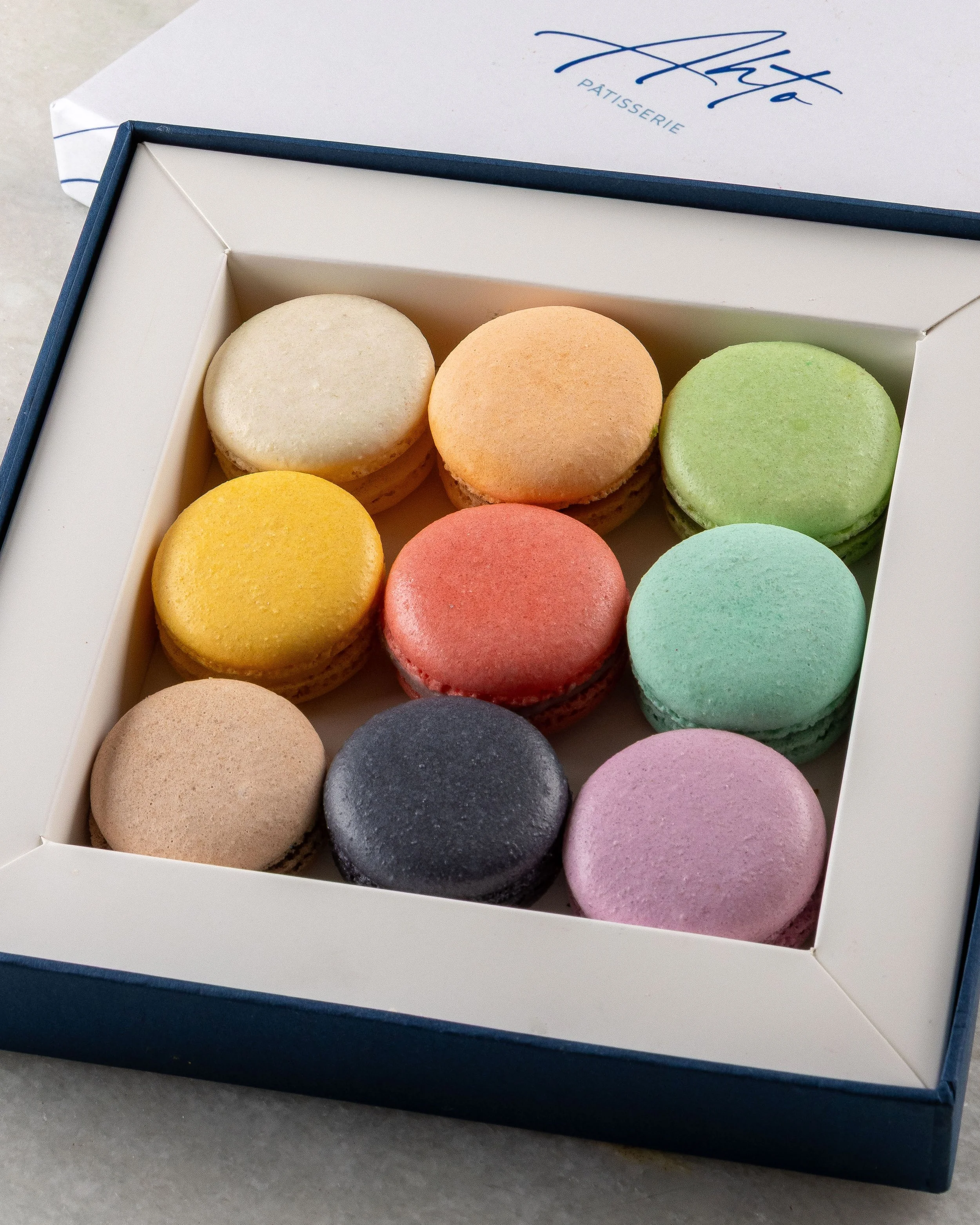 Caixa com nove macarons da Ahto Pâtisserie em diferentes sabores e cores.
