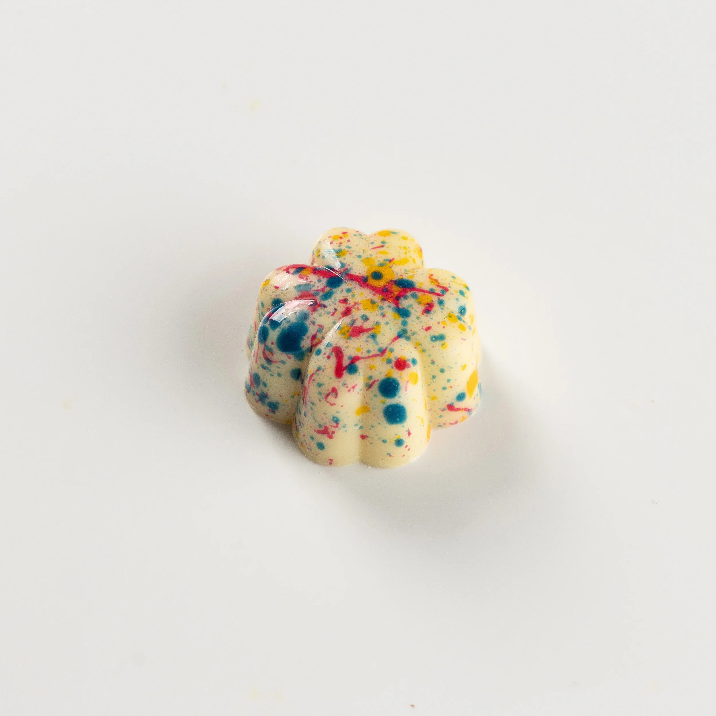 Bombom de sake da Ahto Pâtisserie, com acabamento claro e detalhes coloridos.