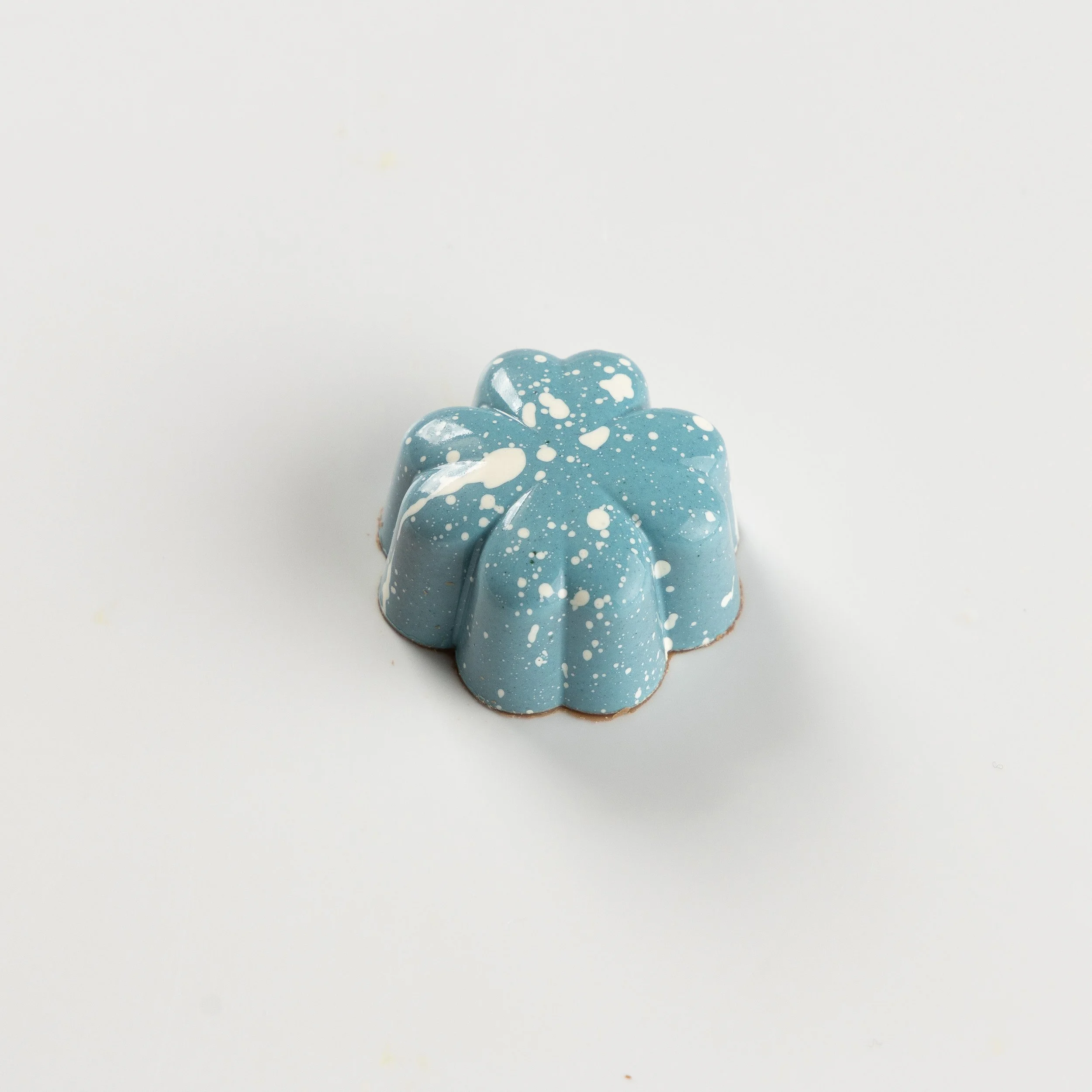Bombom de chocolate ao leite da Ahto Pâtisserie, com acabamento azul claro.
