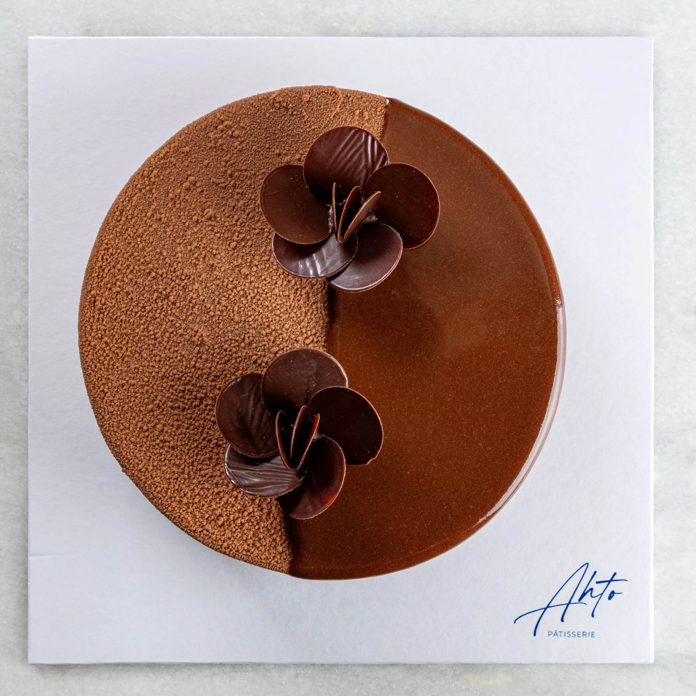 Entremet de chocolate da Ahto Pâtisserie, com acabamento em chocolate e decoração de flores de chocolate.