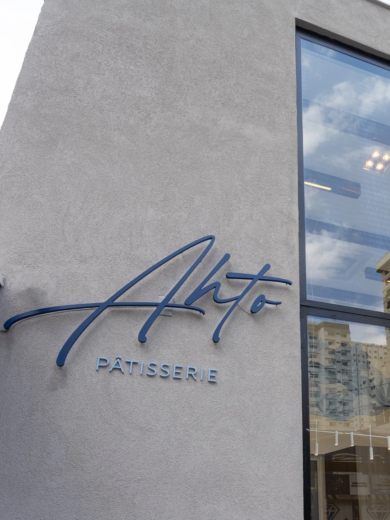 Fachada da Ahto Pâtisserie em São Paulo, com o logotipo da confeitaria instalado na entrada da loja.