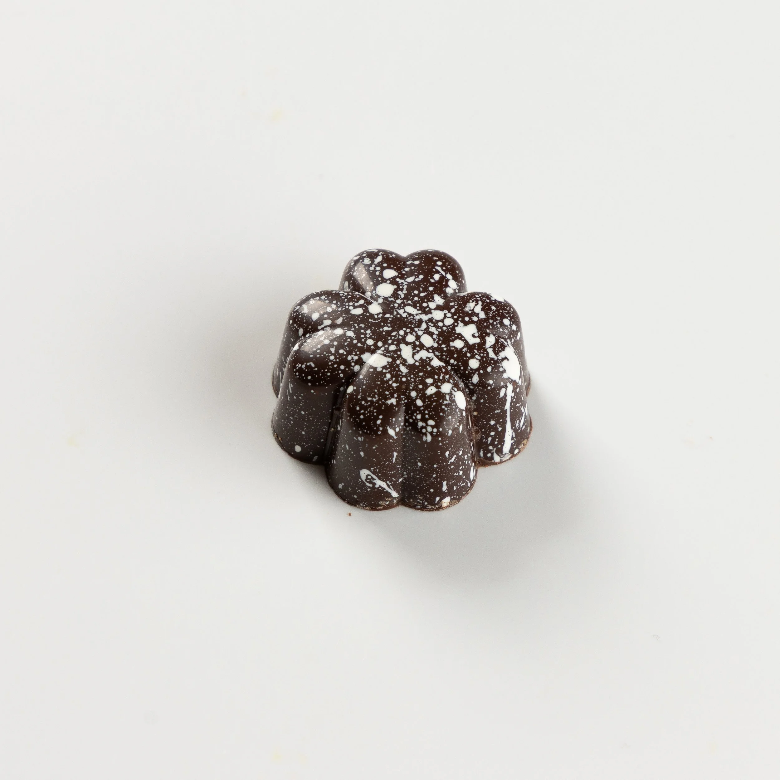 Bombom de coco da Ahto Pâtisserie, com acabamento de chocolate escuro.