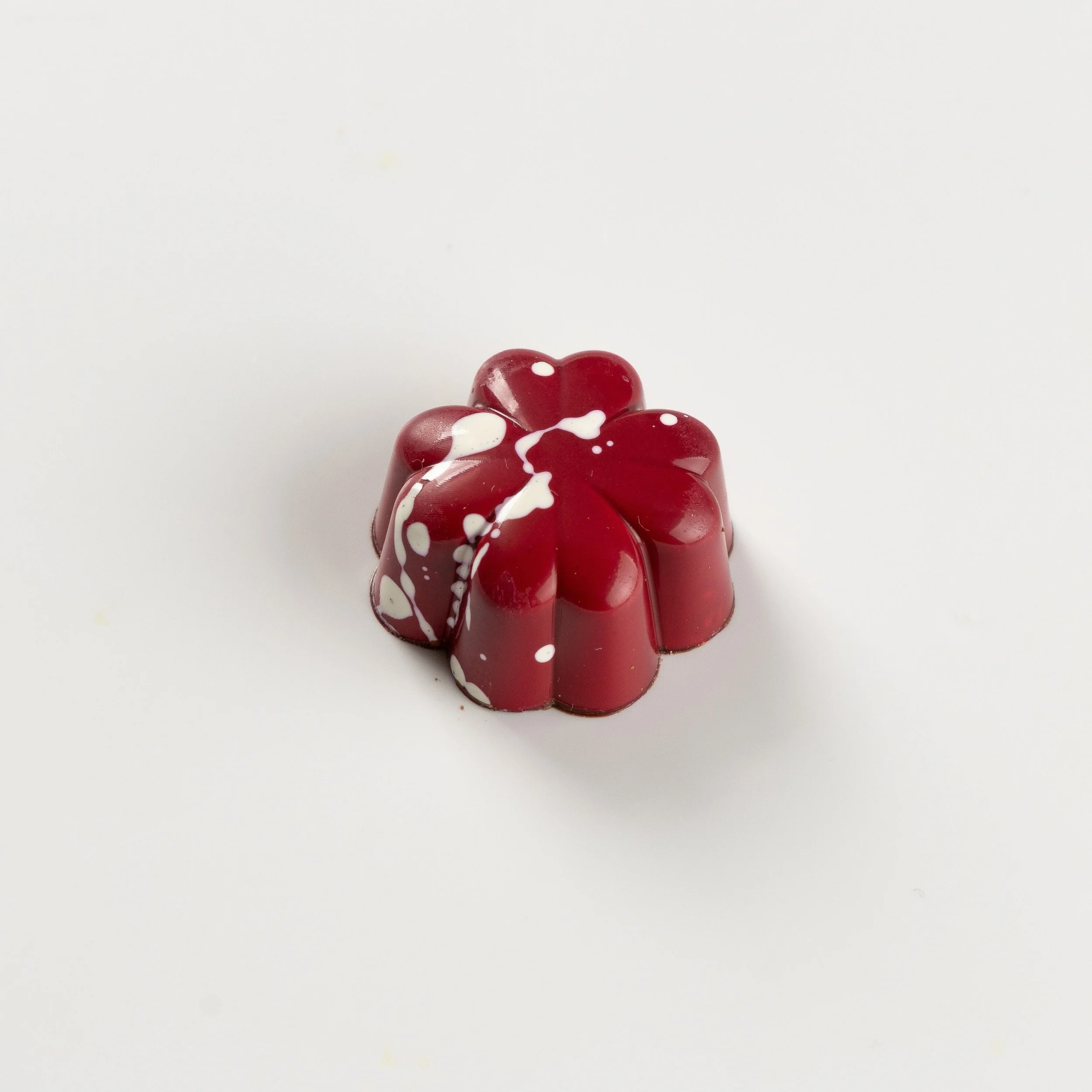 Bombom de caramelo da Ahto Pâtisserie, com acabamento vermelho.