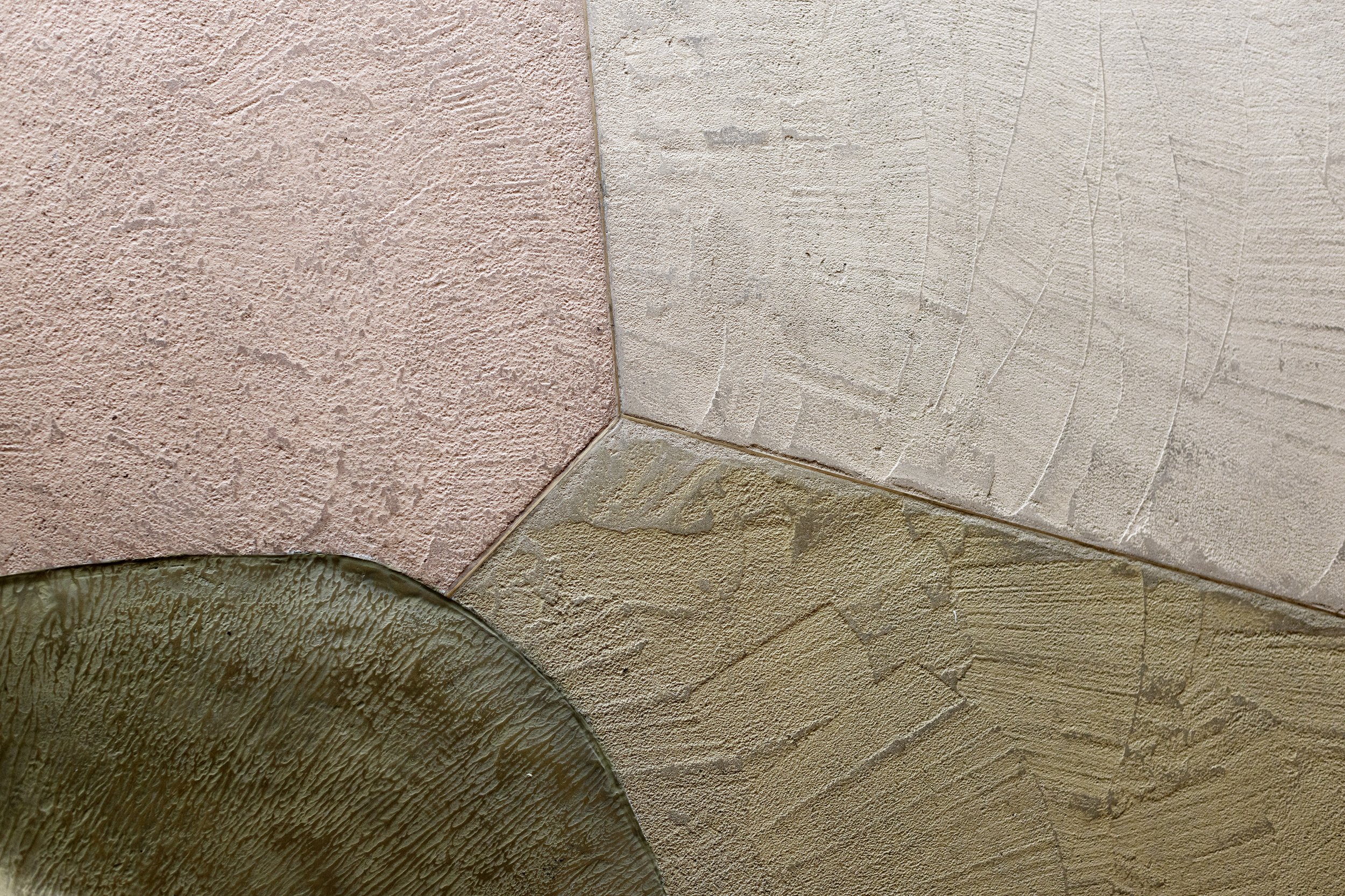 Close-up of textured wall corner with multiple colors of paint including pink, beige, and yellow.