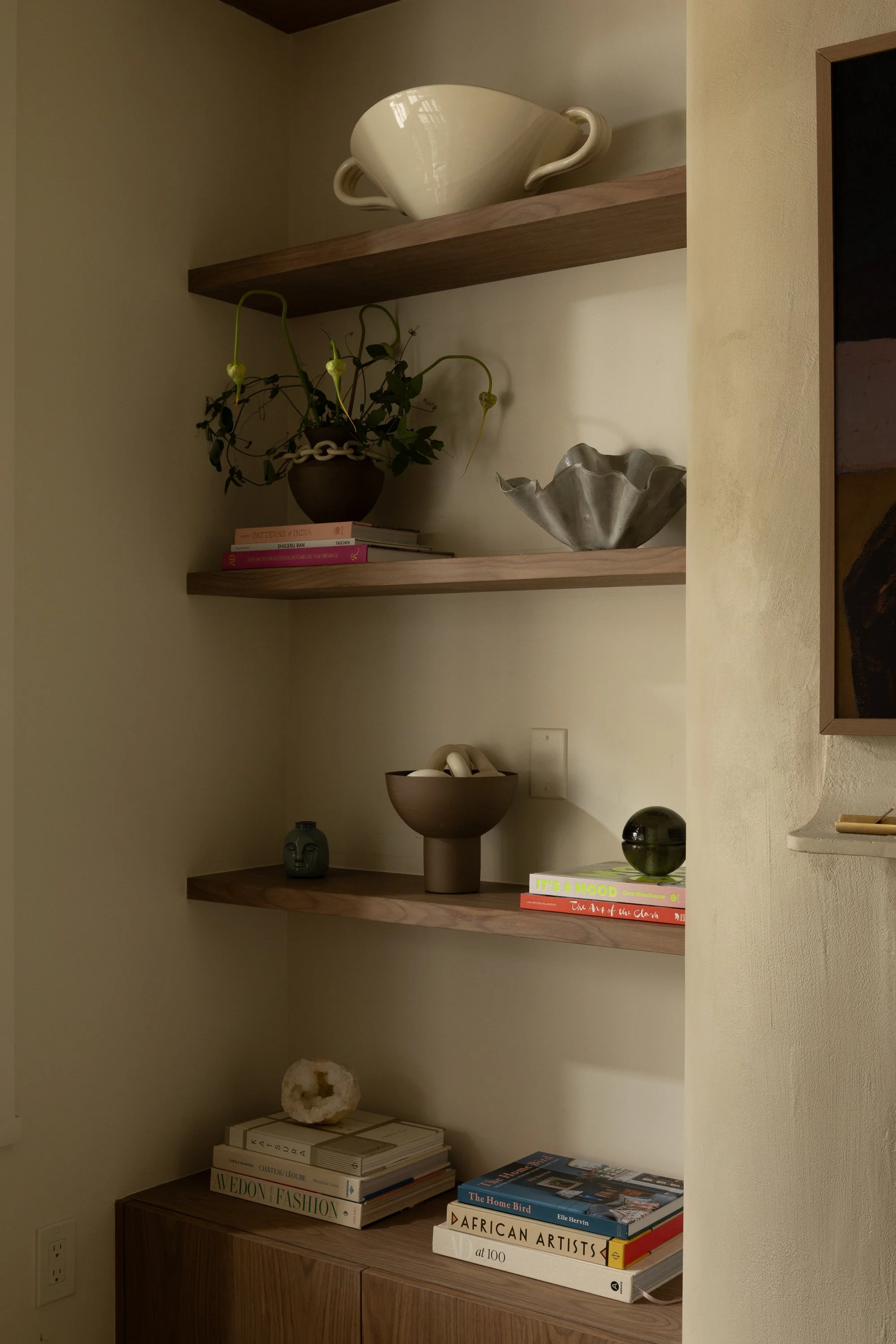 Wooden shelves with decorative items such as books, vases, and art pieces in a cozy corner of a home.