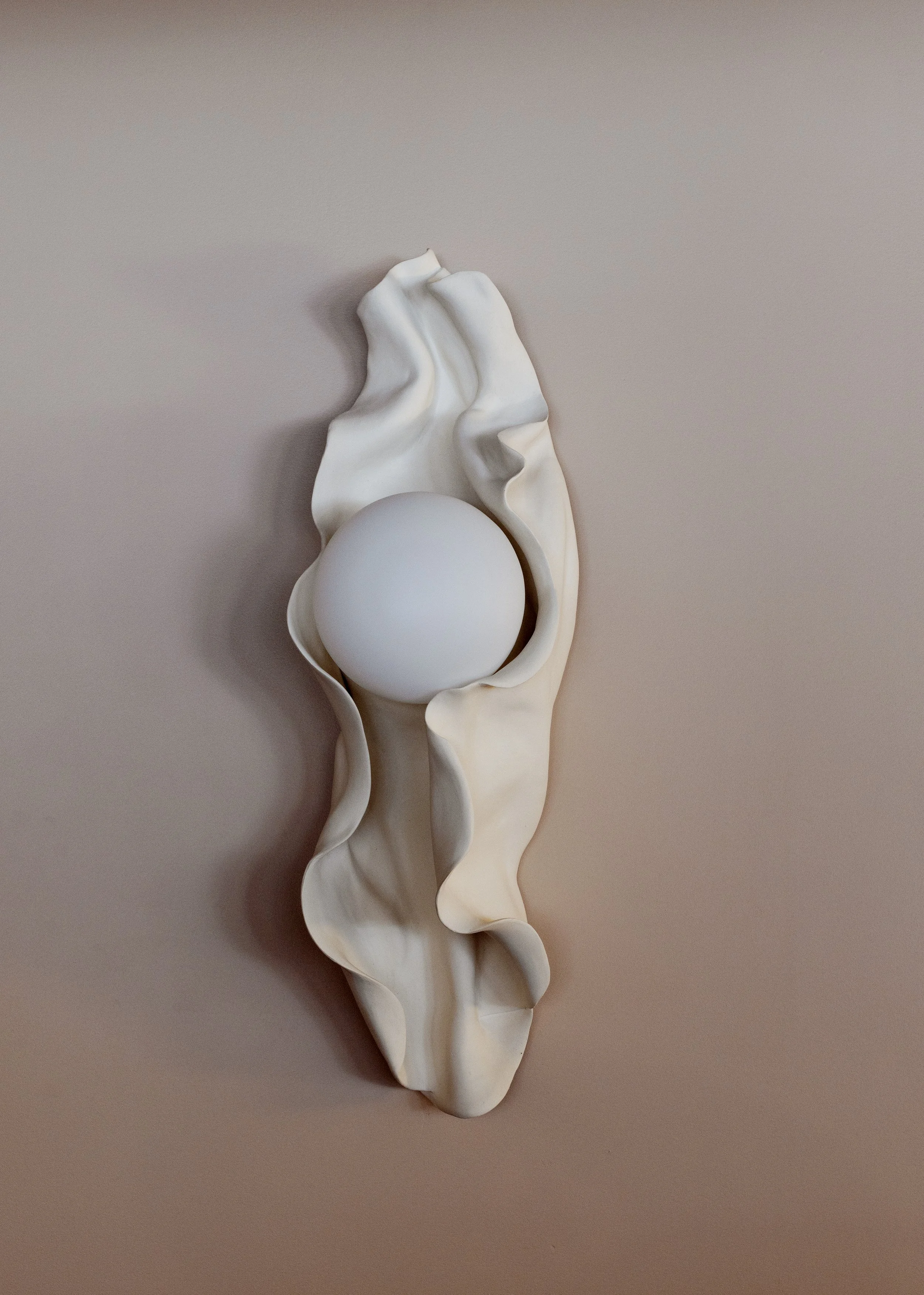 A white egg rests on a white, wavy, shell-shaped dish against a neutral background.