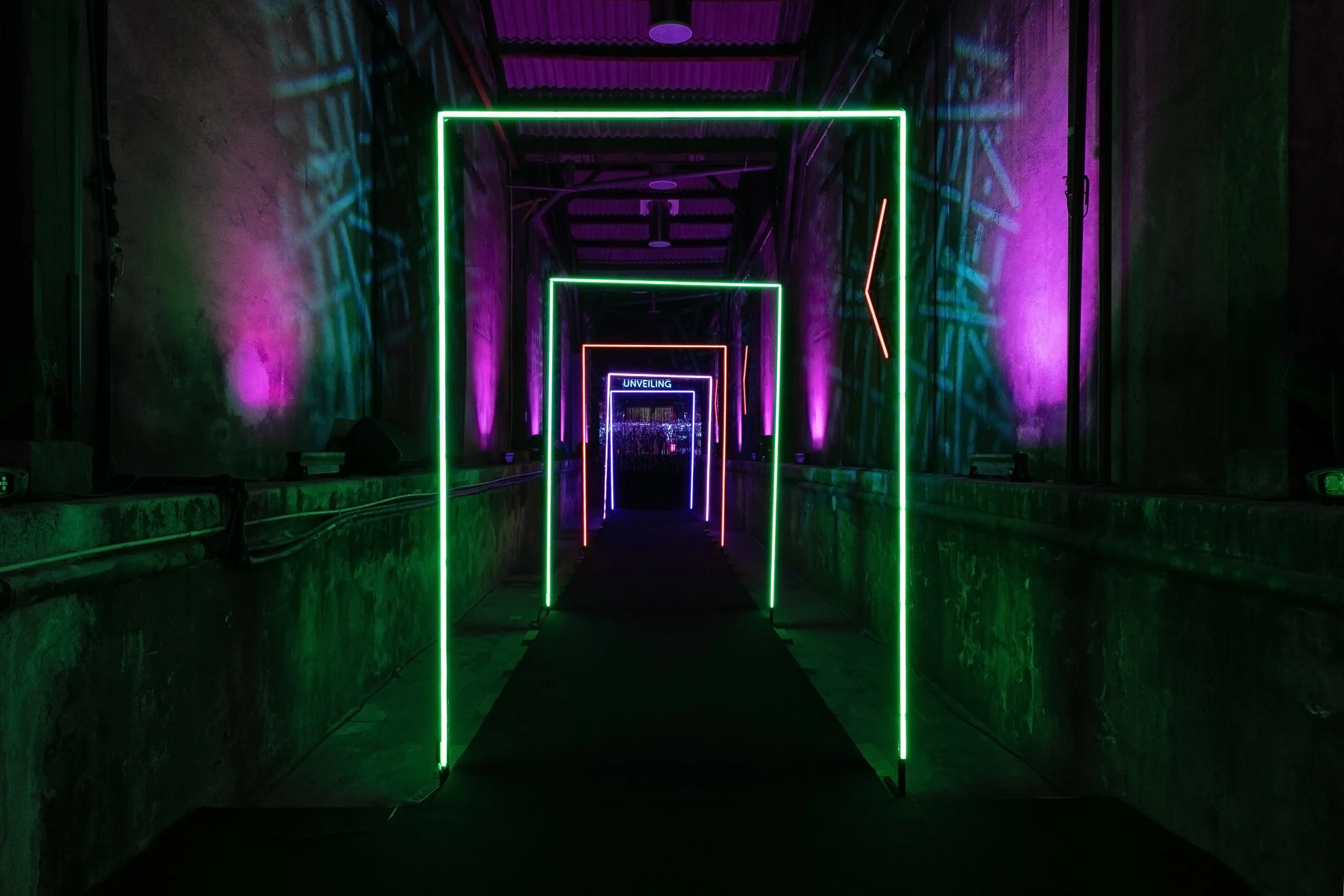 A neon-lit tunnel installation with layered rectangular frames