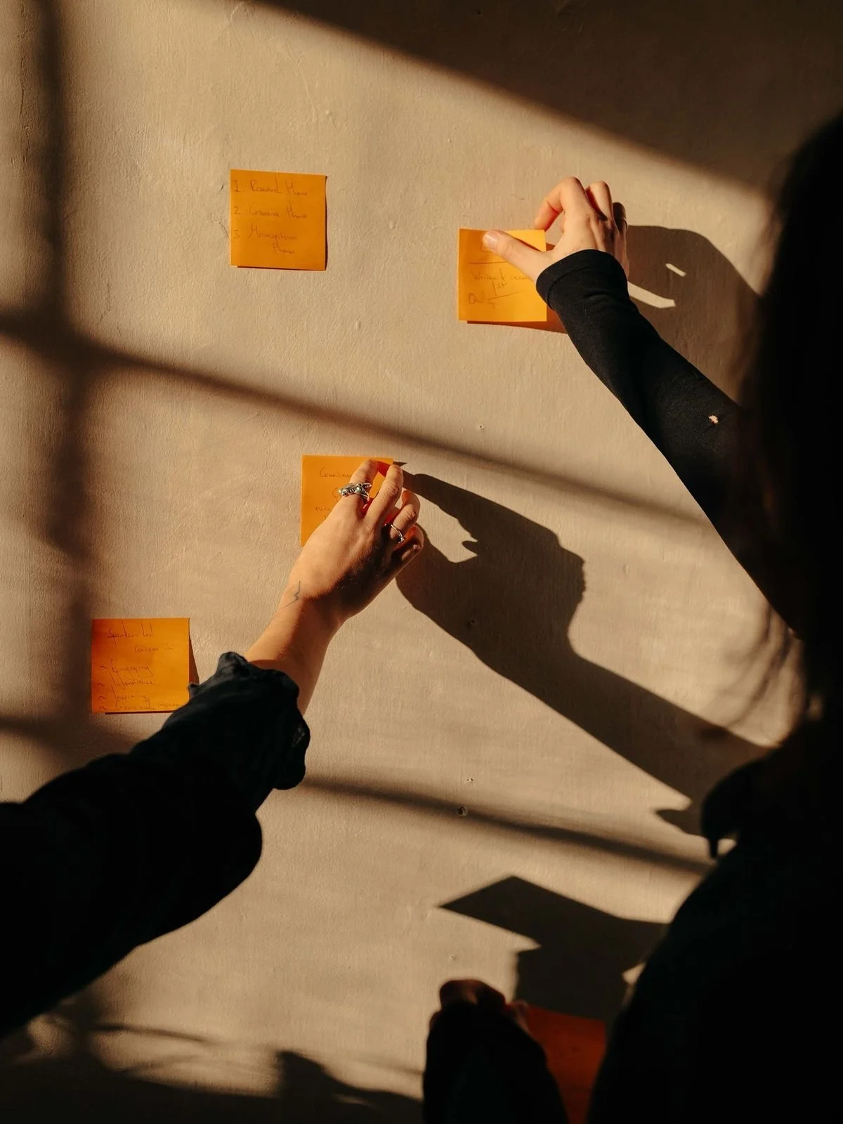 Close-up of hands placing notes on a wall during a working session