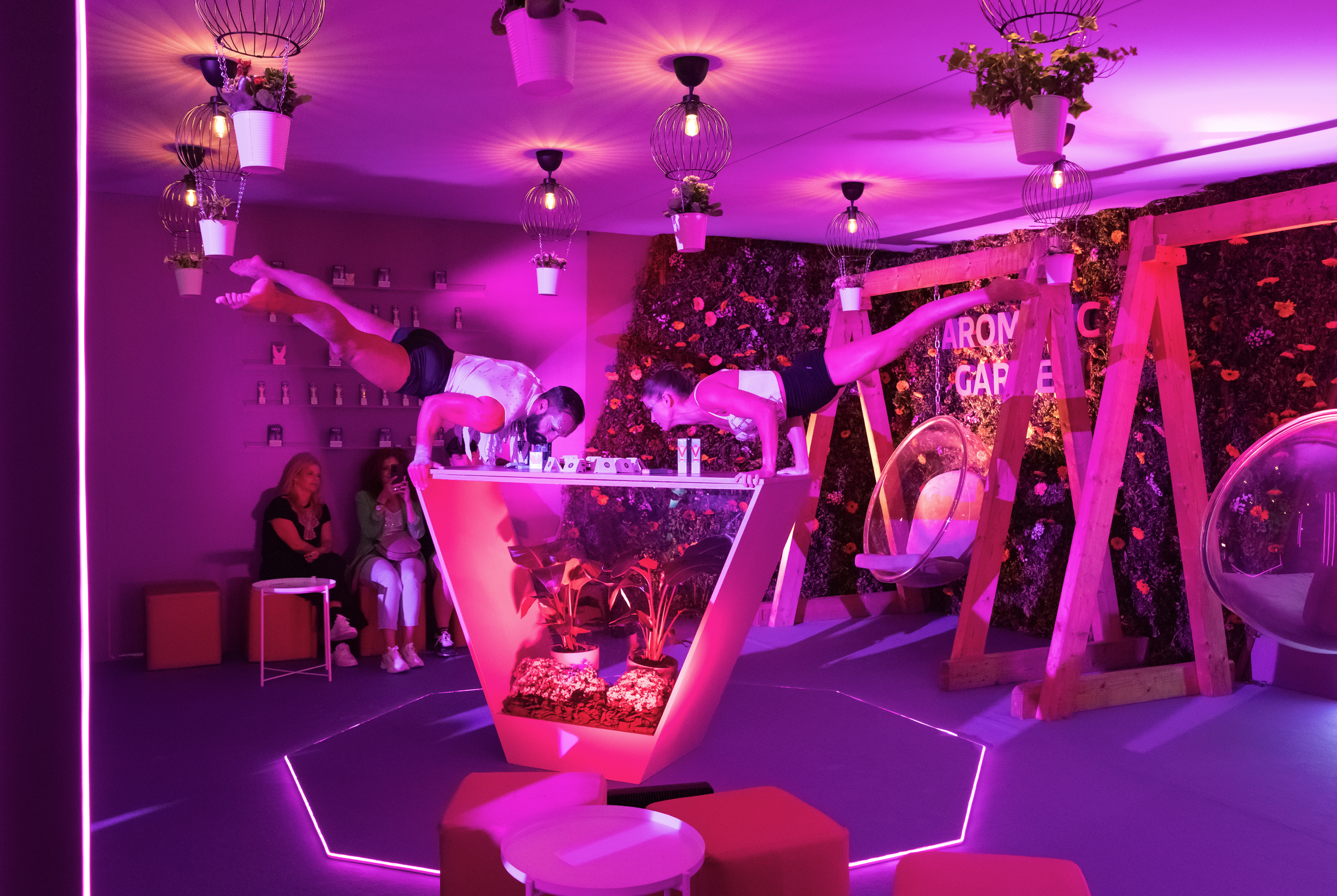 Performers under pink and purple lighting at an immersive indoor event