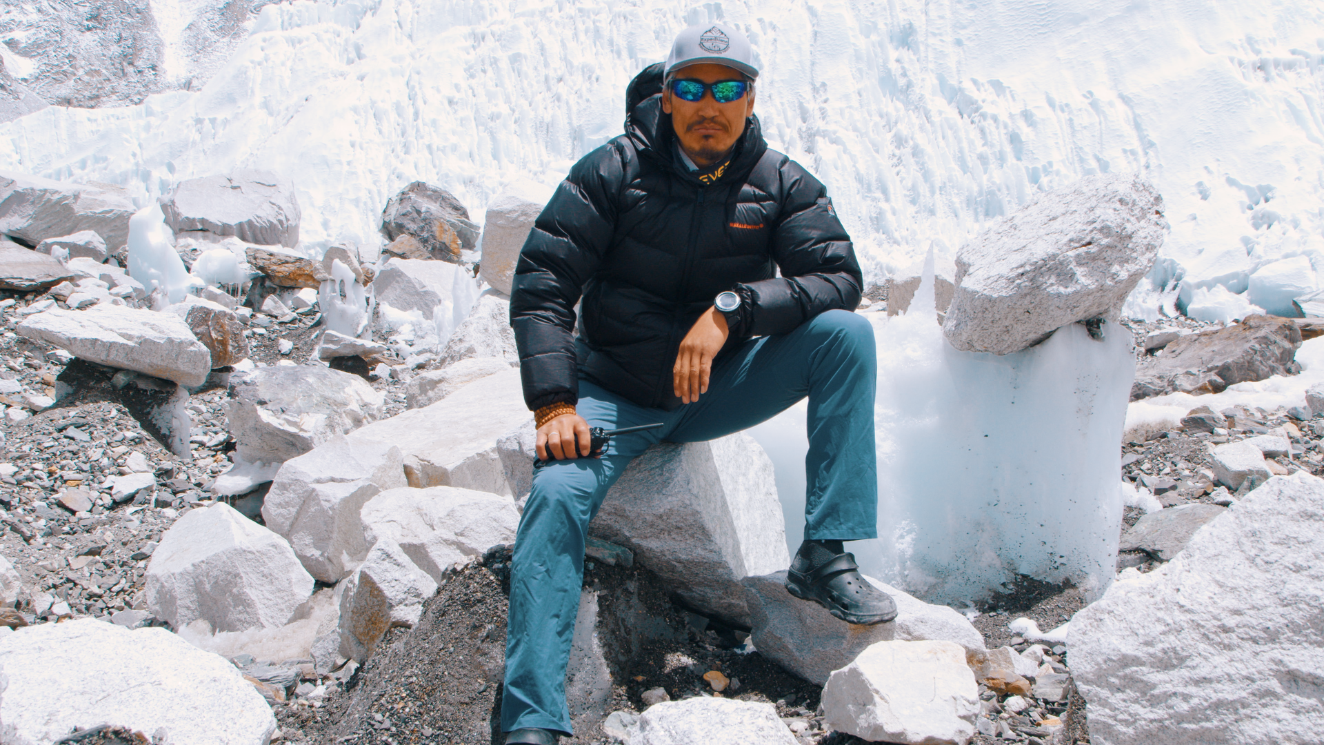 Guide de haute montagne assis sur un bloc rocheux devant la cascade de glace du Khumbu