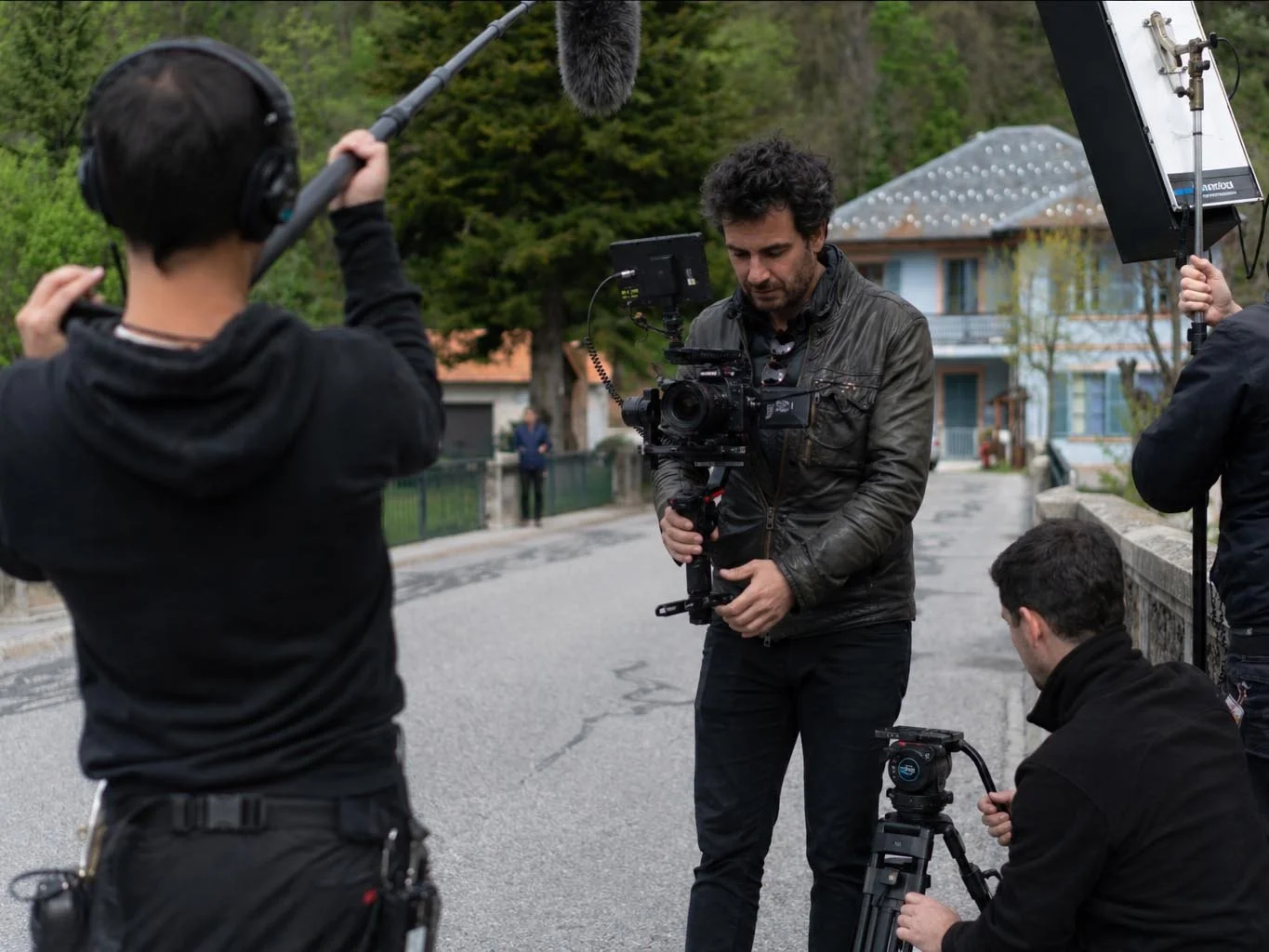 A film crew working outdoors with a camera rig and boom microphone.