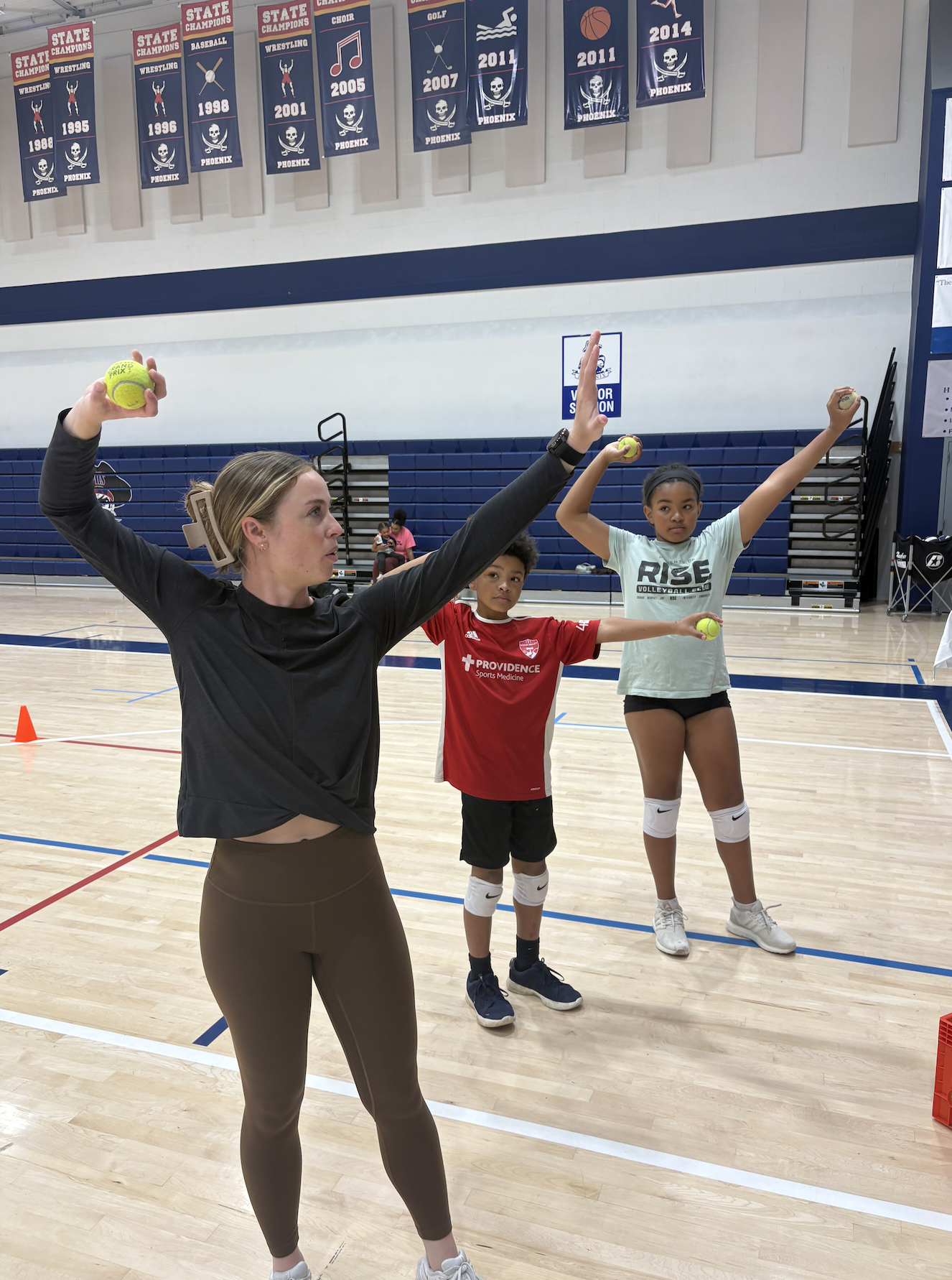 Blonde women training two young volleyball players