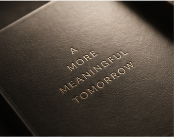 Close-up of a black book cover with the words 'A MORE MEANINGFUL TOMORROW' embossed in gold lettering.