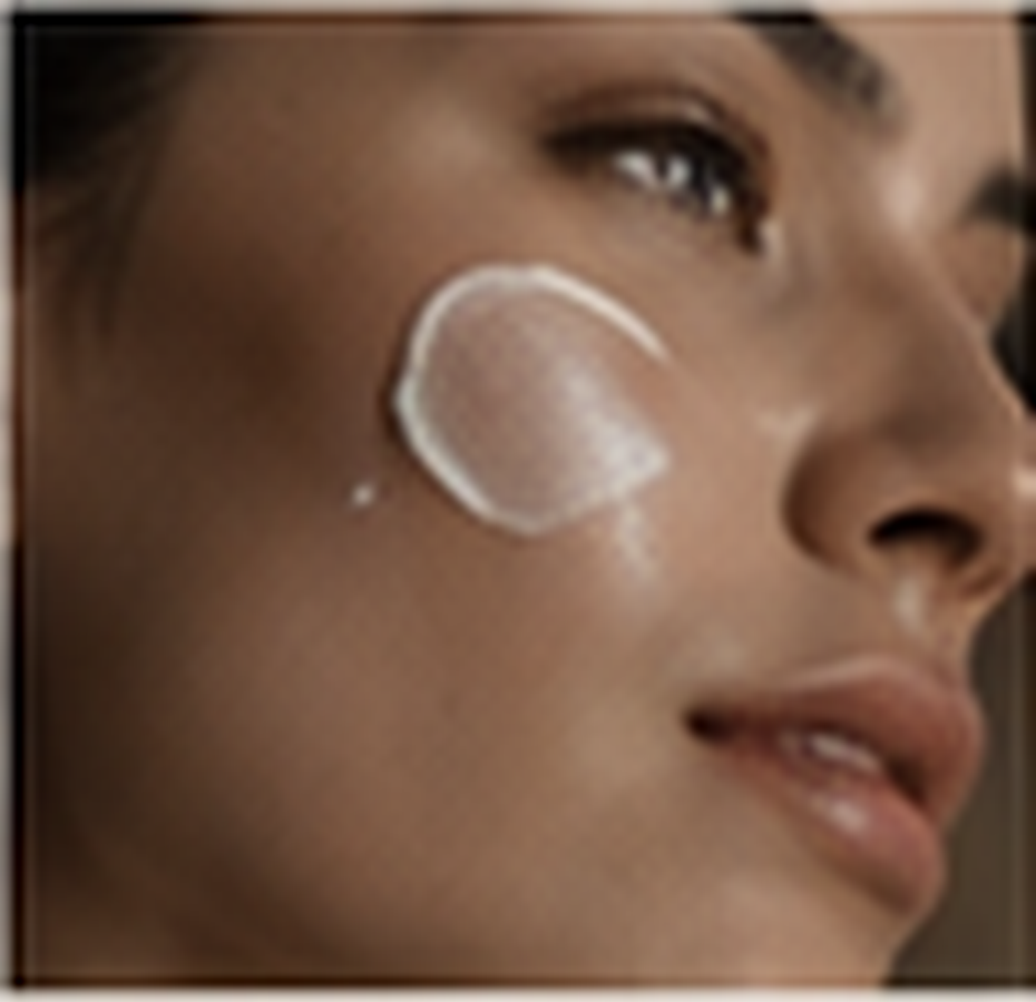 Close-up of a person applying moisturizer or skincare product to their face with a small amount of cream on their cheek.