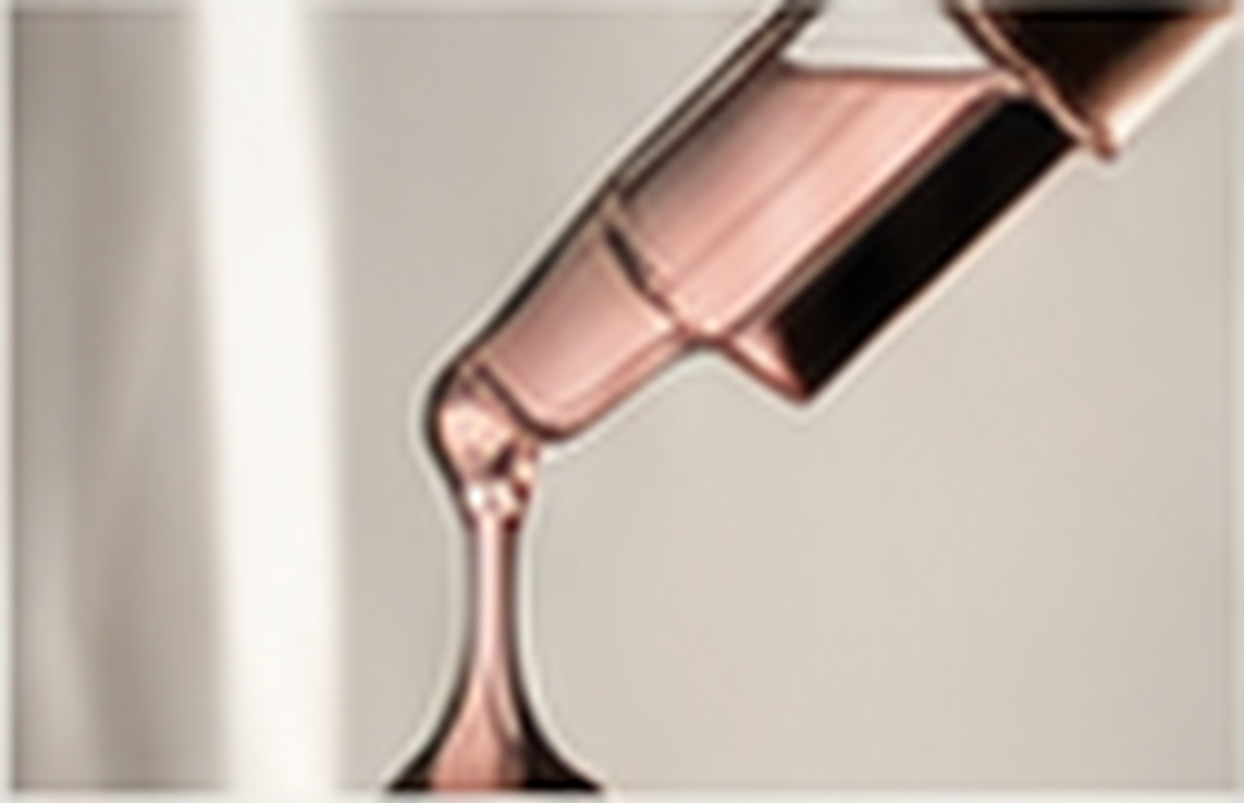 Close-up of a funnel with pink liquid pouring into it, positioned against a light background.