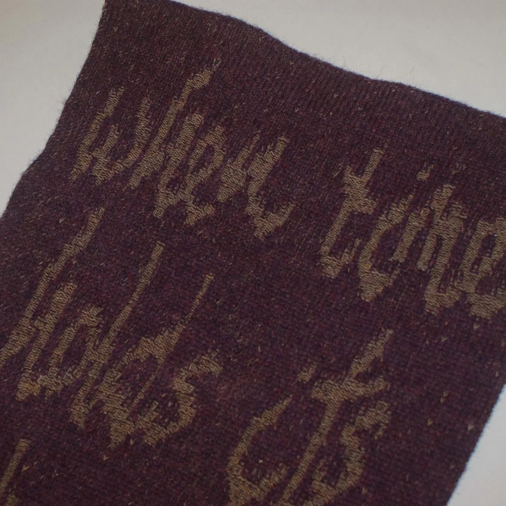Close-up view of a dark maroon or burgundy sock with a textured ribbed pattern and tan-colored embroidered text that appears to spell "DICK'S" on the side.
