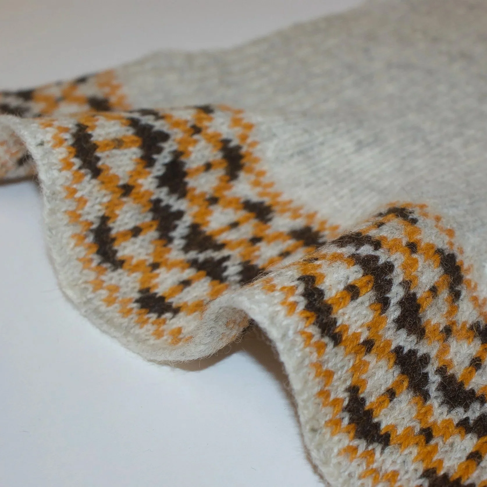 Close-up of a gray fabric with a plaid pattern in orange, black, and white, showing the fabric texture.