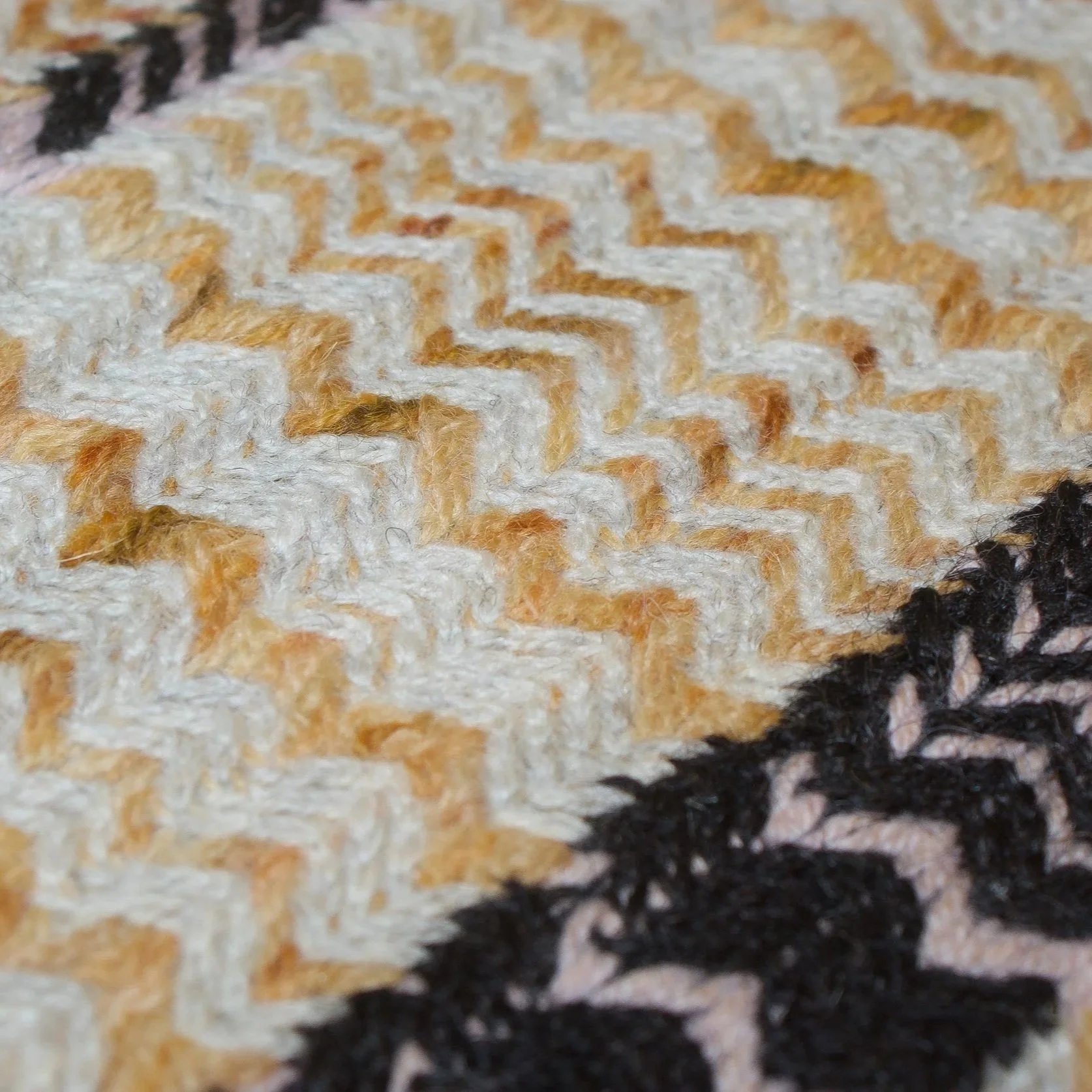 Close-up of fabric with a zigzag pattern in shades of beige, white, black, and brown.