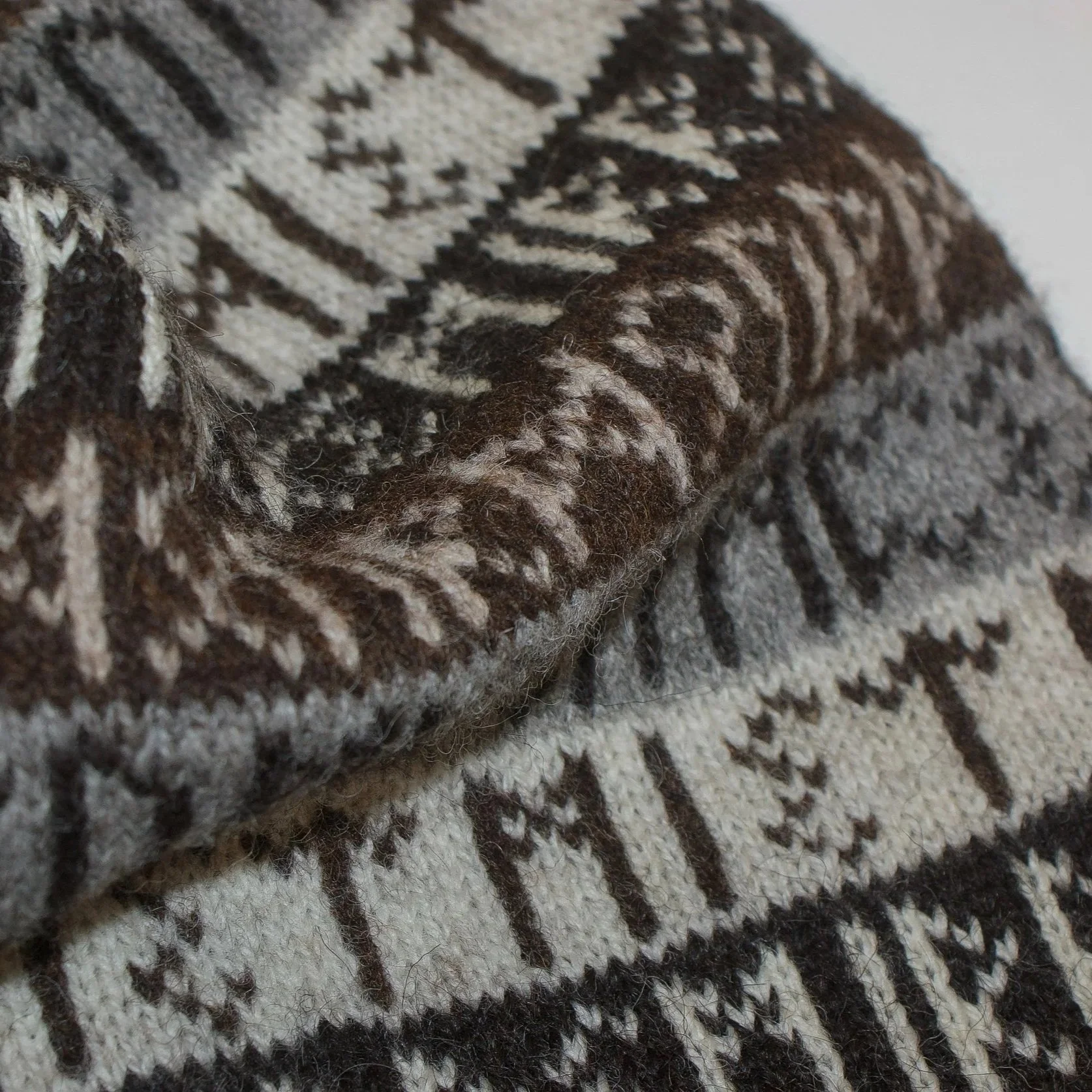 Close-up of a knitted fabric with a beige background and brown norse writing.