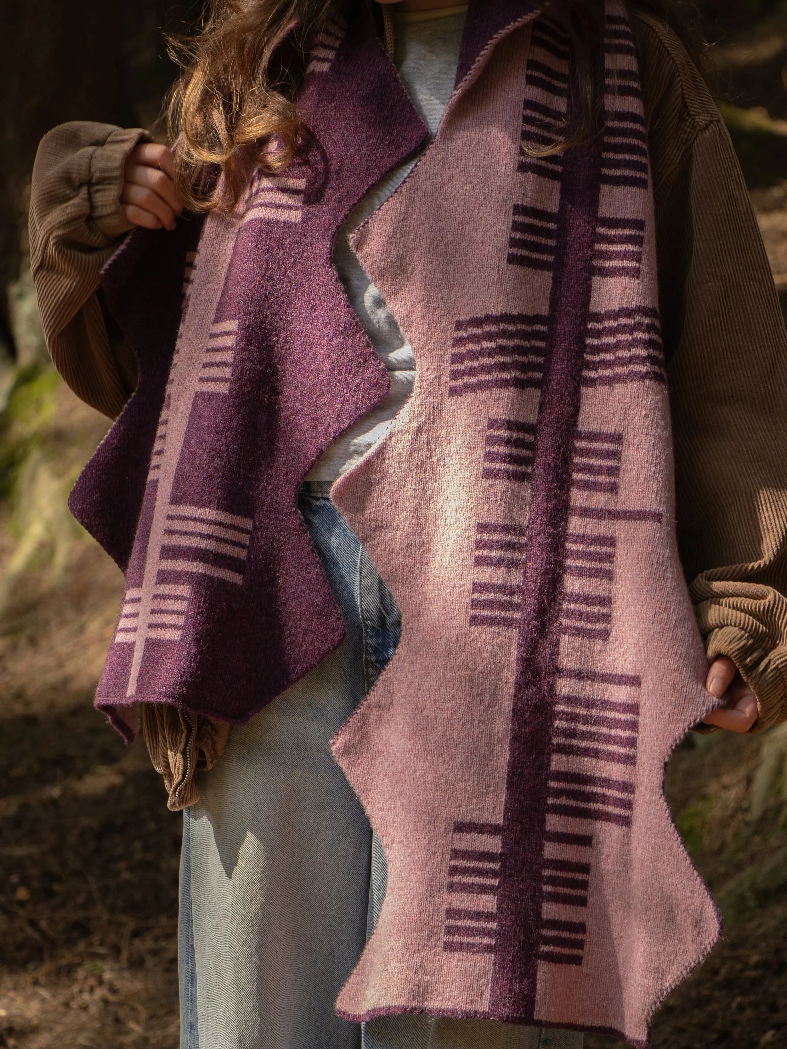 Person wearing a 'watch where you put your boots in the heather' scarf by Lizzie Forbes. Ogham script on knitting.