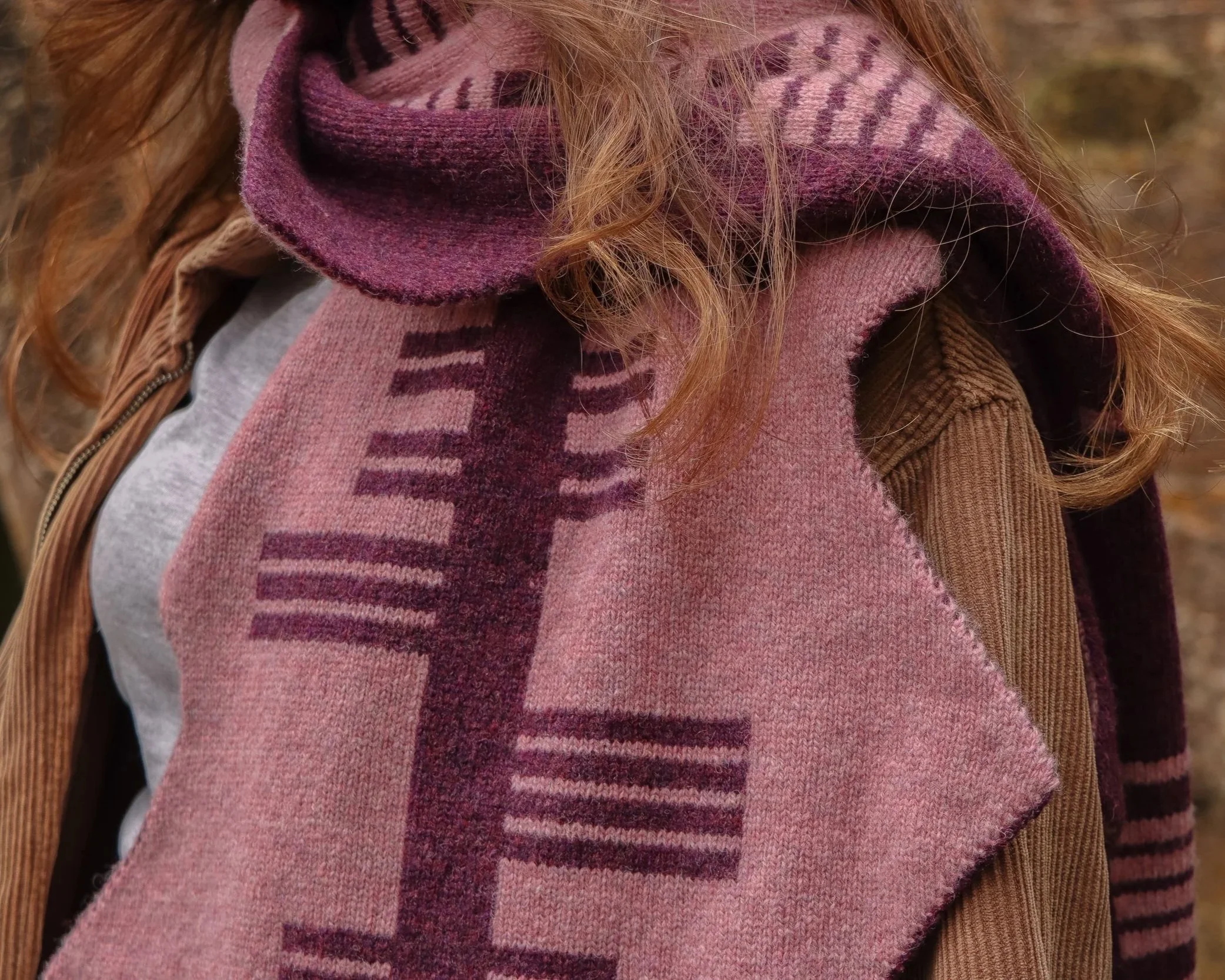 Close-up of a person wearing a pink and purple ogham scarf.