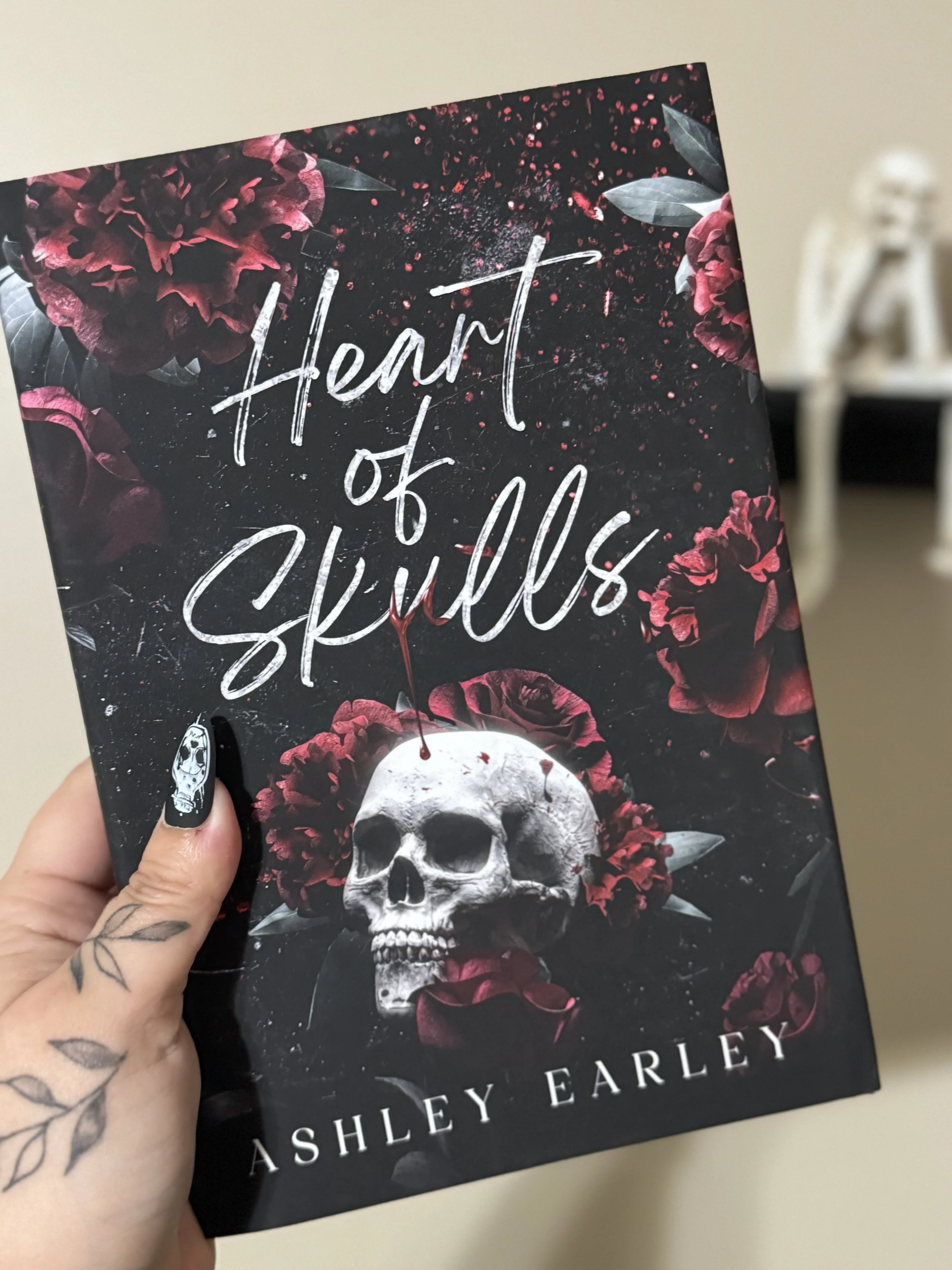 Cover of a book titled 'Heart of Stars' by Shelley Earley featuring a skull surrounded by dark red flowers and petals against a dark background.