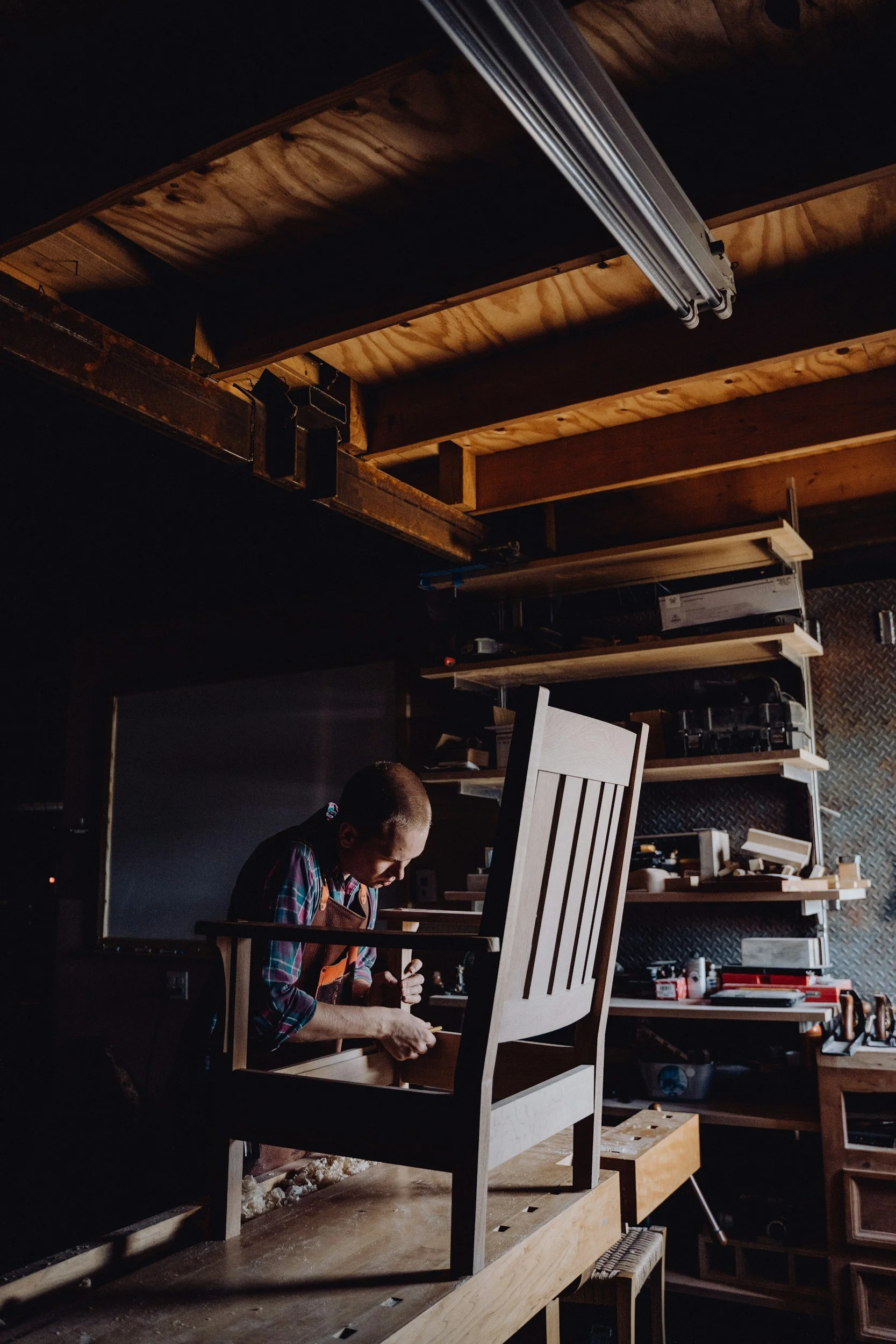 Craftsman working on a wooden chair in a furniture workshop