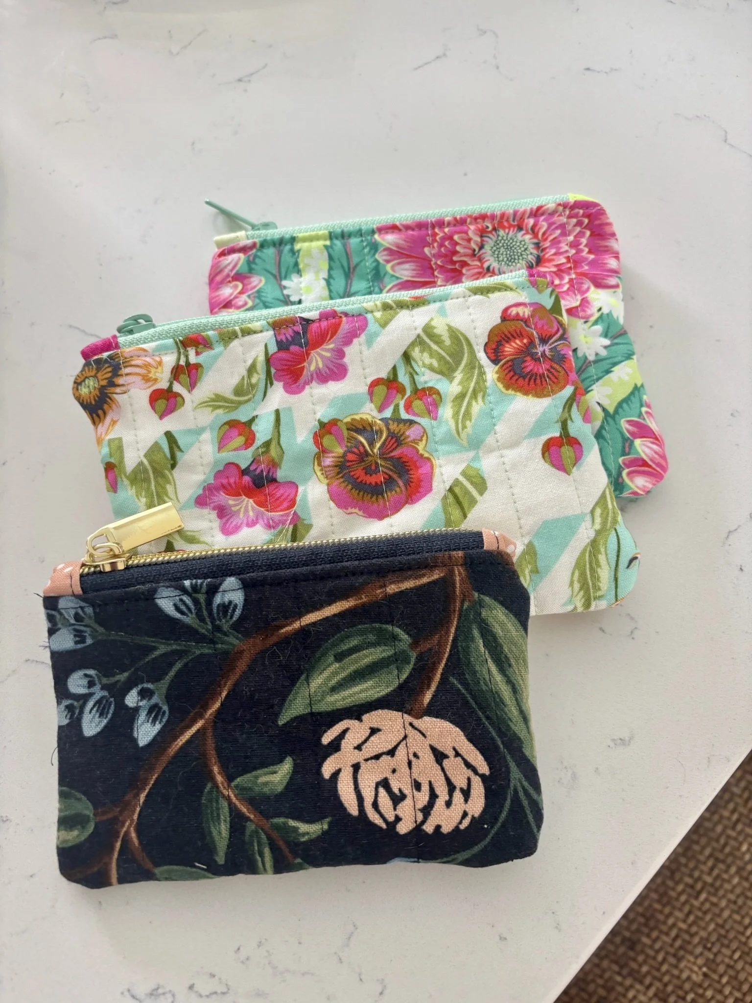 Three colorful zippered pouches with floral patterns