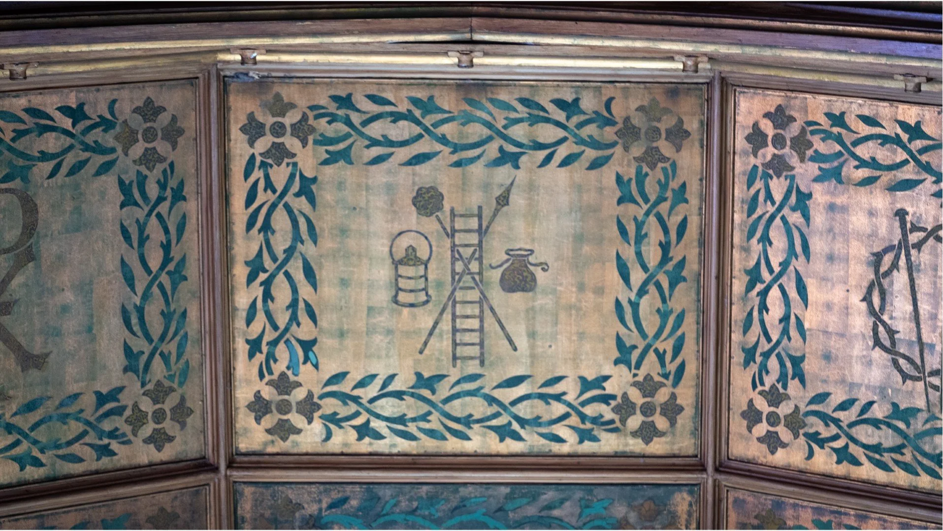 Antique painted wooden panel with blue floral vine borders and central illustrations of a ladder, chair, and ornate vase
