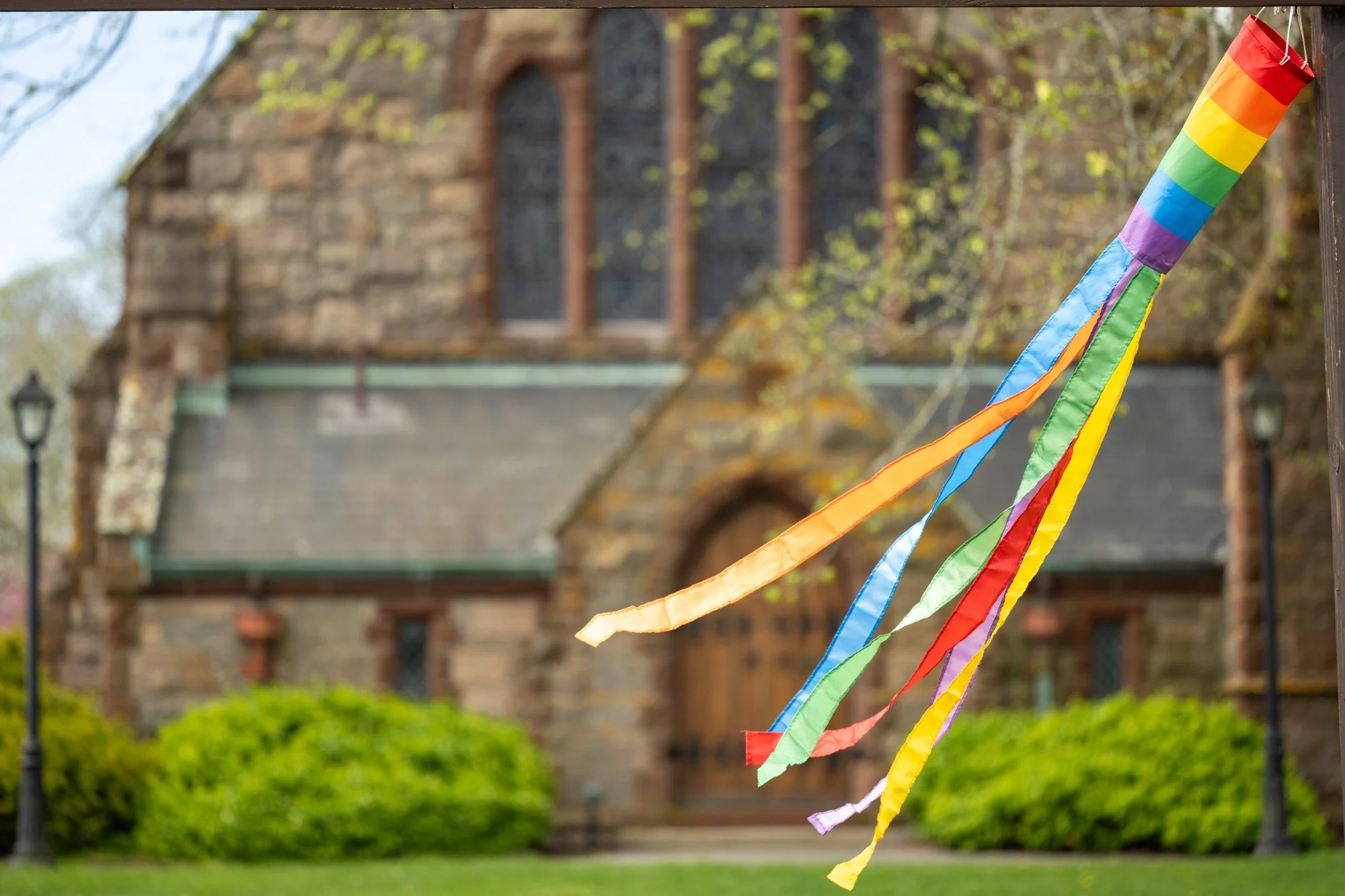 Rainbow windsock hanging outside a historic stone church